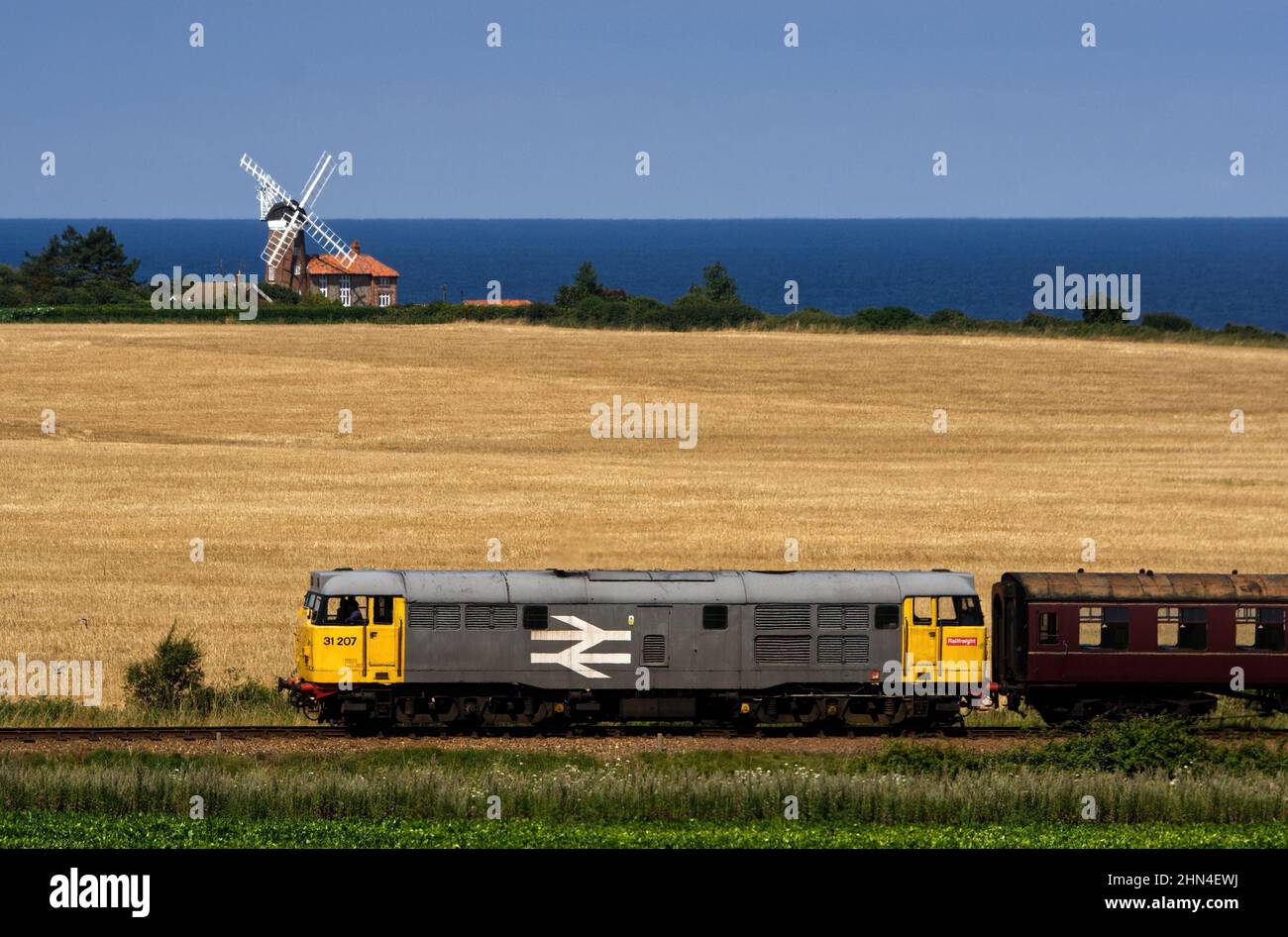 Una locomotiva diesel Railnight Class 31 che passa per il mulino a vento di Weybourne sulla North Norfolk Railway, Norfolk, Regno Unito. Foto Stock