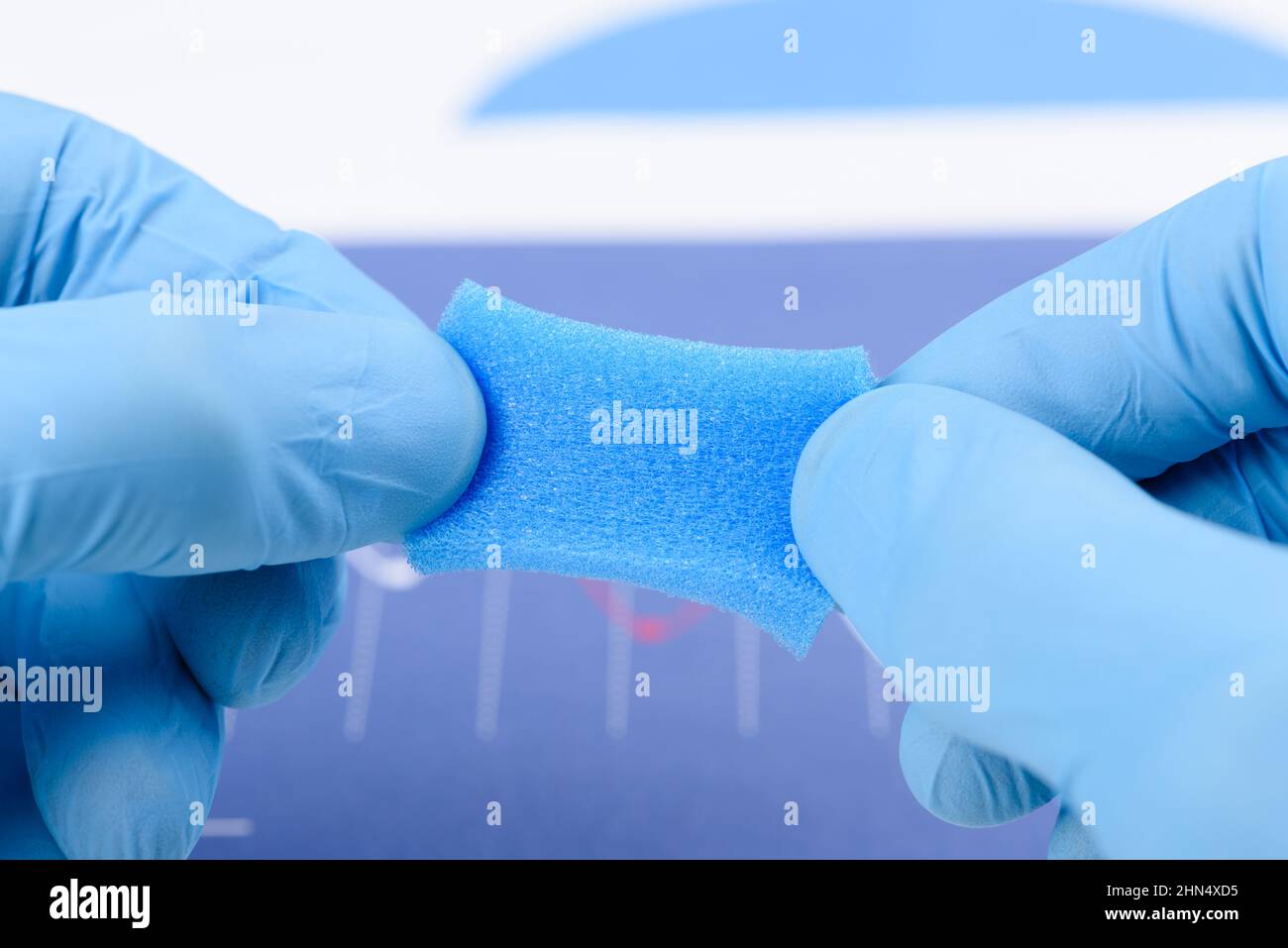 Materiale simile a spugna porosa blu stirato nelle mani dello scienziato in laboratorio. Ricerca di materiale con nuovo concetto di proprietà. Foto Stock