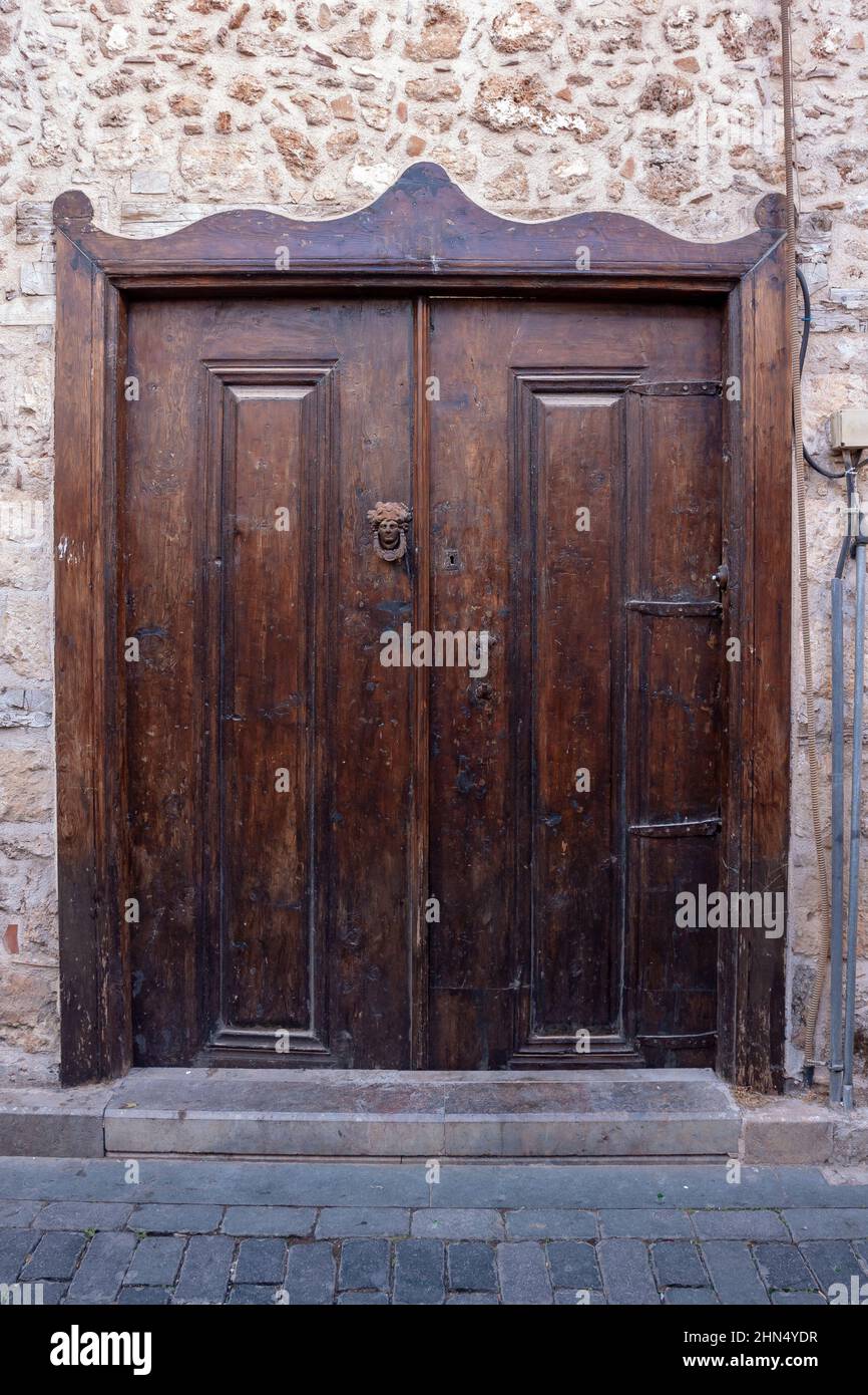 Vecchia porta in legno shabby con battente per porta forgiato e pomello per porta. Foto Stock