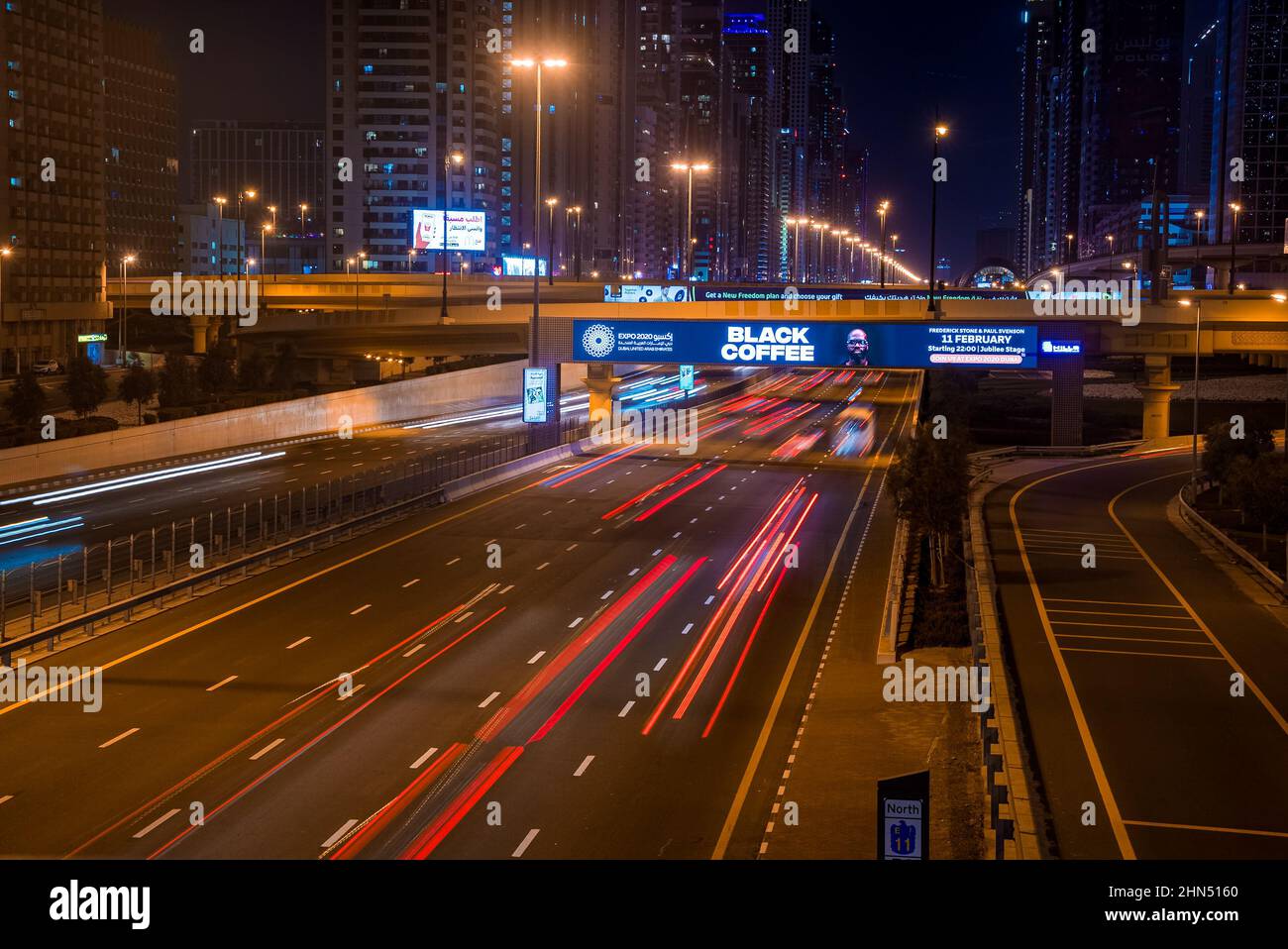 Lunga esposizione di auto in movimento sulla strada notturna di Dubai. Foto Stock
