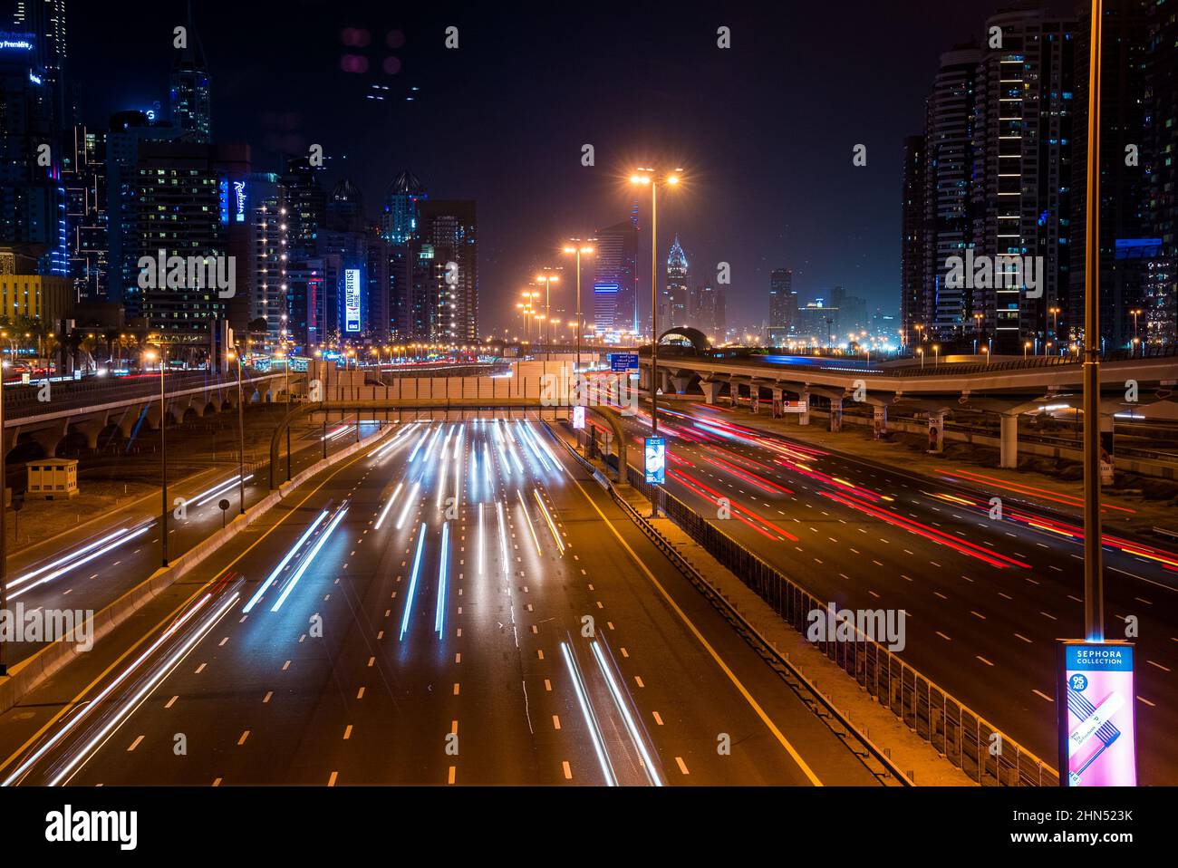 Lunga esposizione di auto in movimento sulla strada notturna di Dubai. Foto Stock