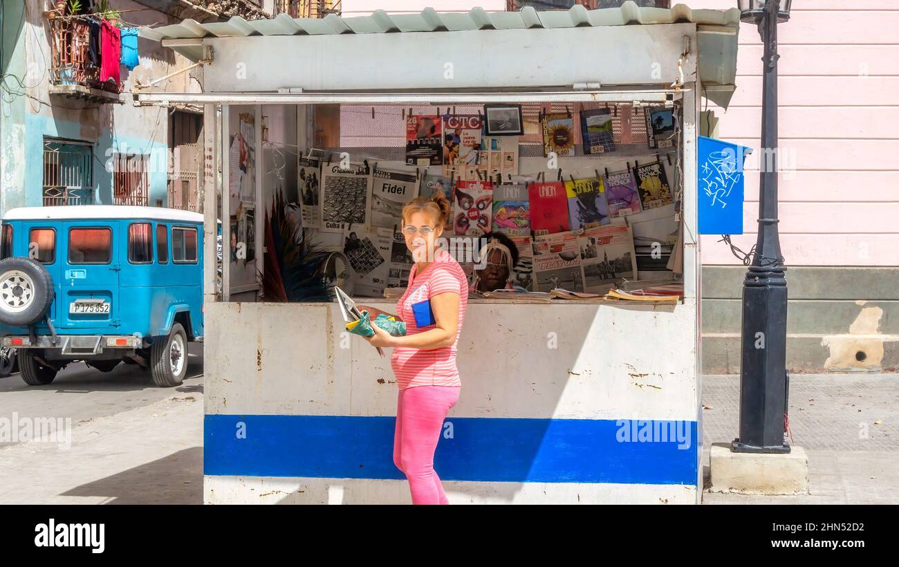 Una donna cubana acquista un giornale o altri supporti stampati da un chiosco gestito dal governo. Foto Stock