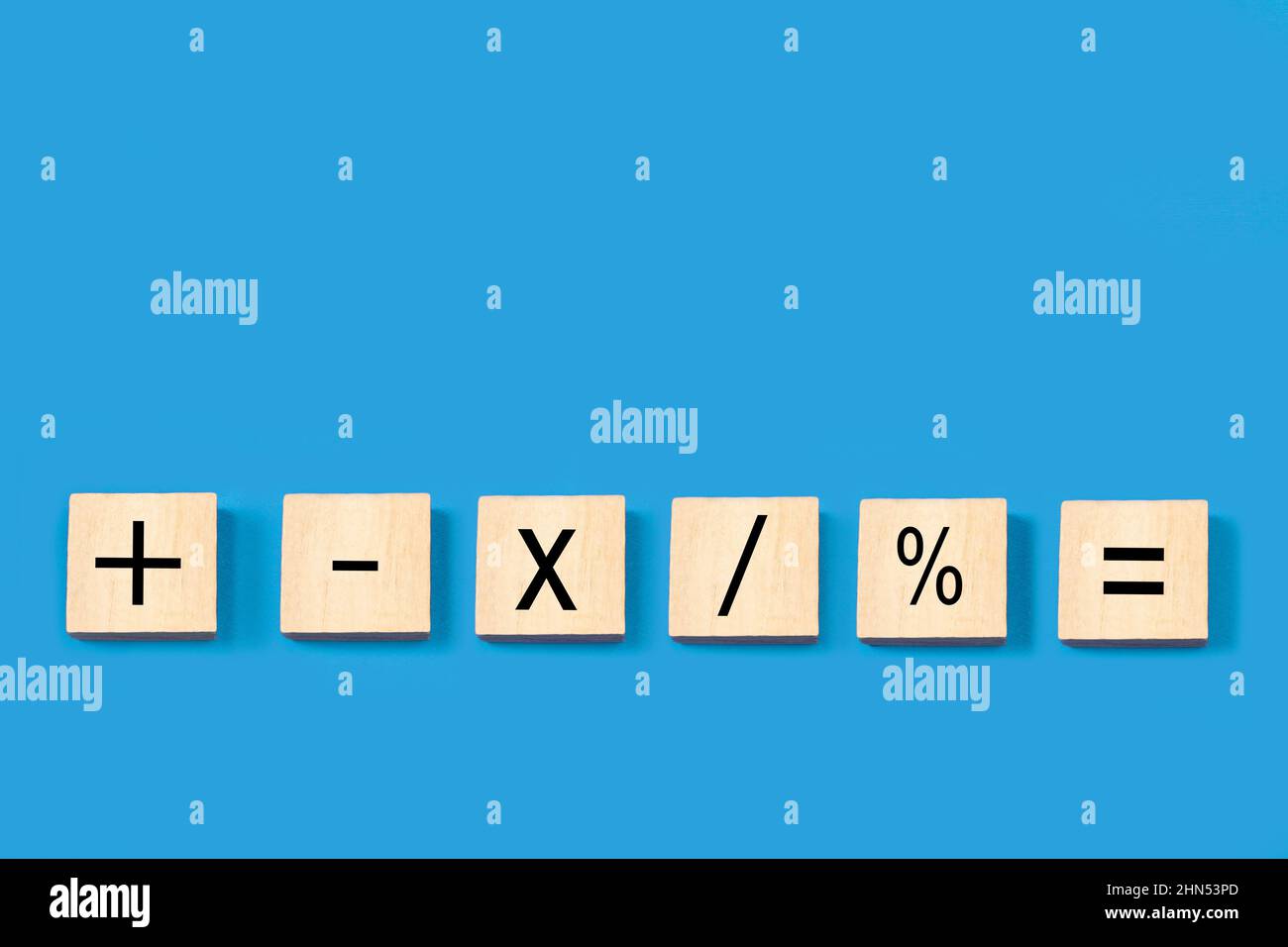 Segni matematici in blocchi di legno su sfondo blu con spazio di copia Foto Stock
