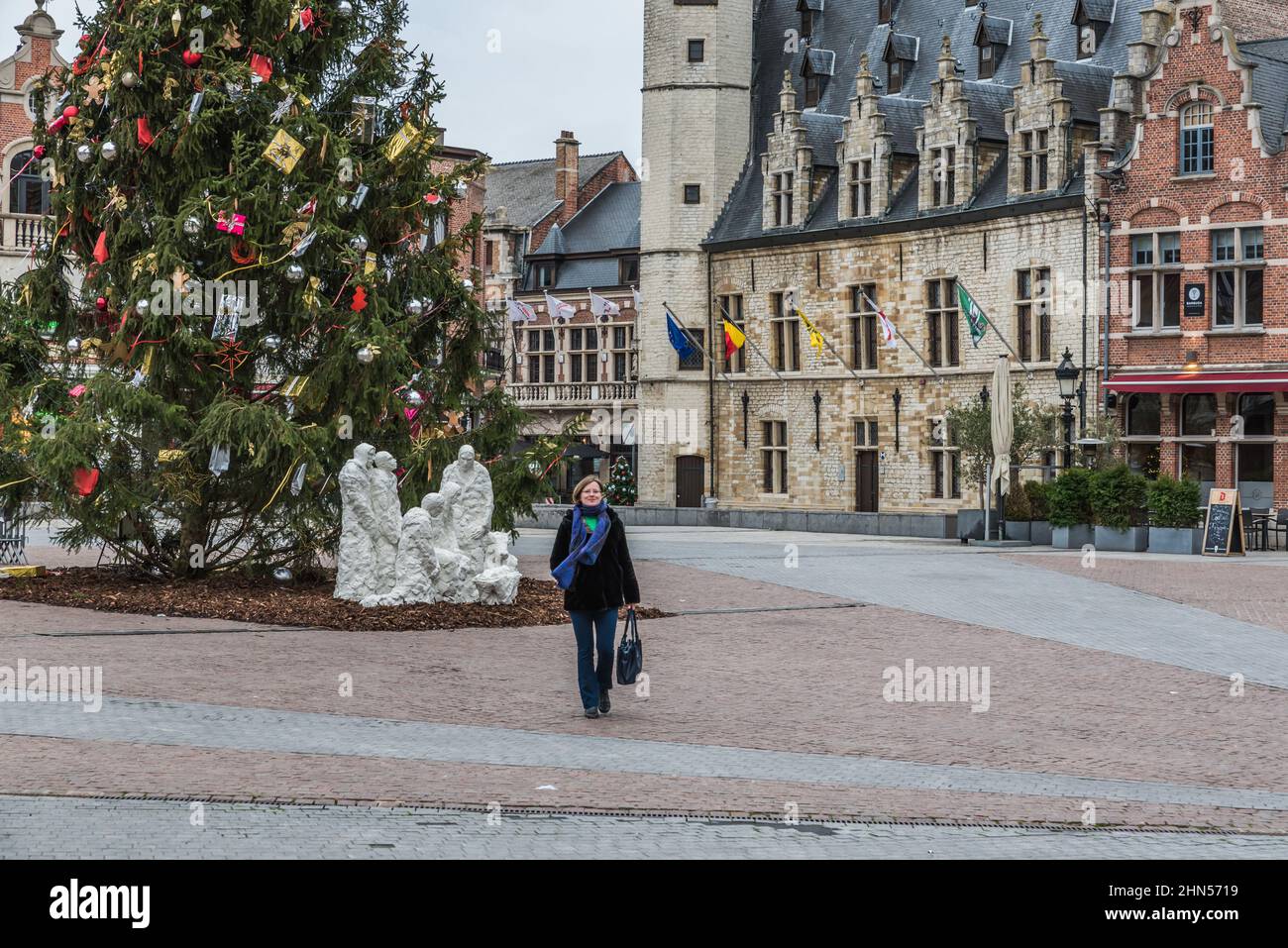 Dendermonde, Fiandre Orientali - Belgio - 12 08 2018: Donna che cammina sulla vecchia piazza del mercato con facciate di mediëval e un albero di Natale decorato Foto Stock