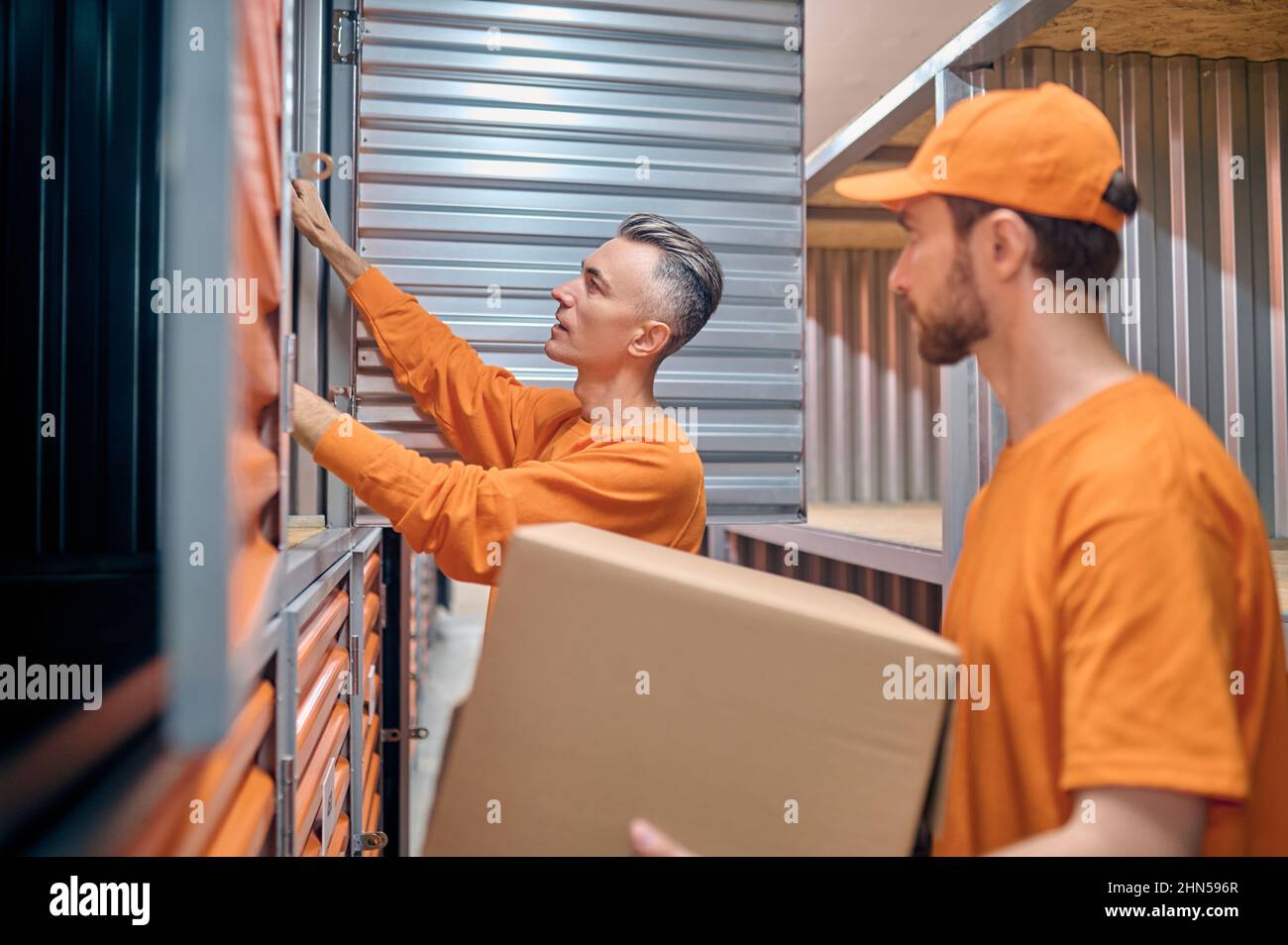 Due dipendenti del magazzino caucasico che containerizzano merci in scatola Foto Stock