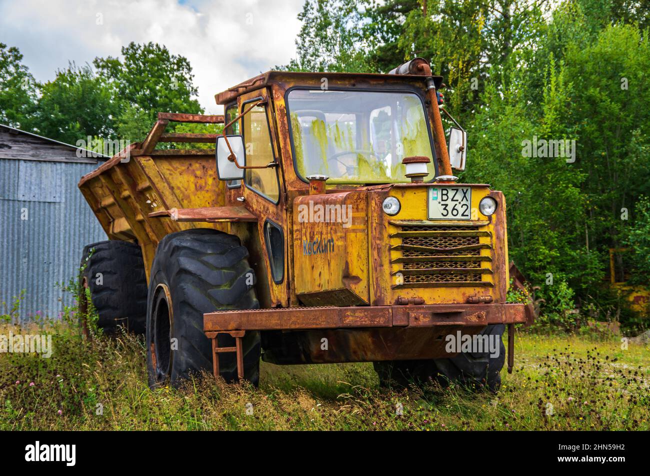 Vecchio e arrugginito camion di scarico Kockum abbandonato di fronte a un capannone di stagno in ambiente rurale e rustico, vicino Mellerud, Dalsland, Svezia. Foto Stock