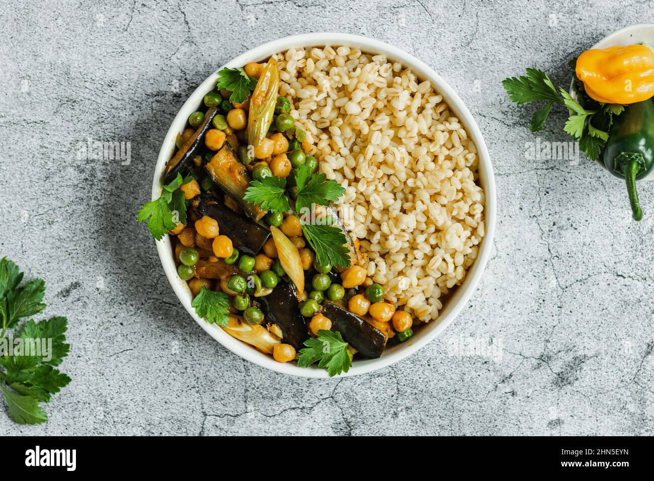 Melanzane ceci piselli vegetariano curry vegano con bulgur in una padella su sfondo grigio, vista dall'alto. Cucina indiana, cibo sano, vegano, base vegetale. Foto Stock