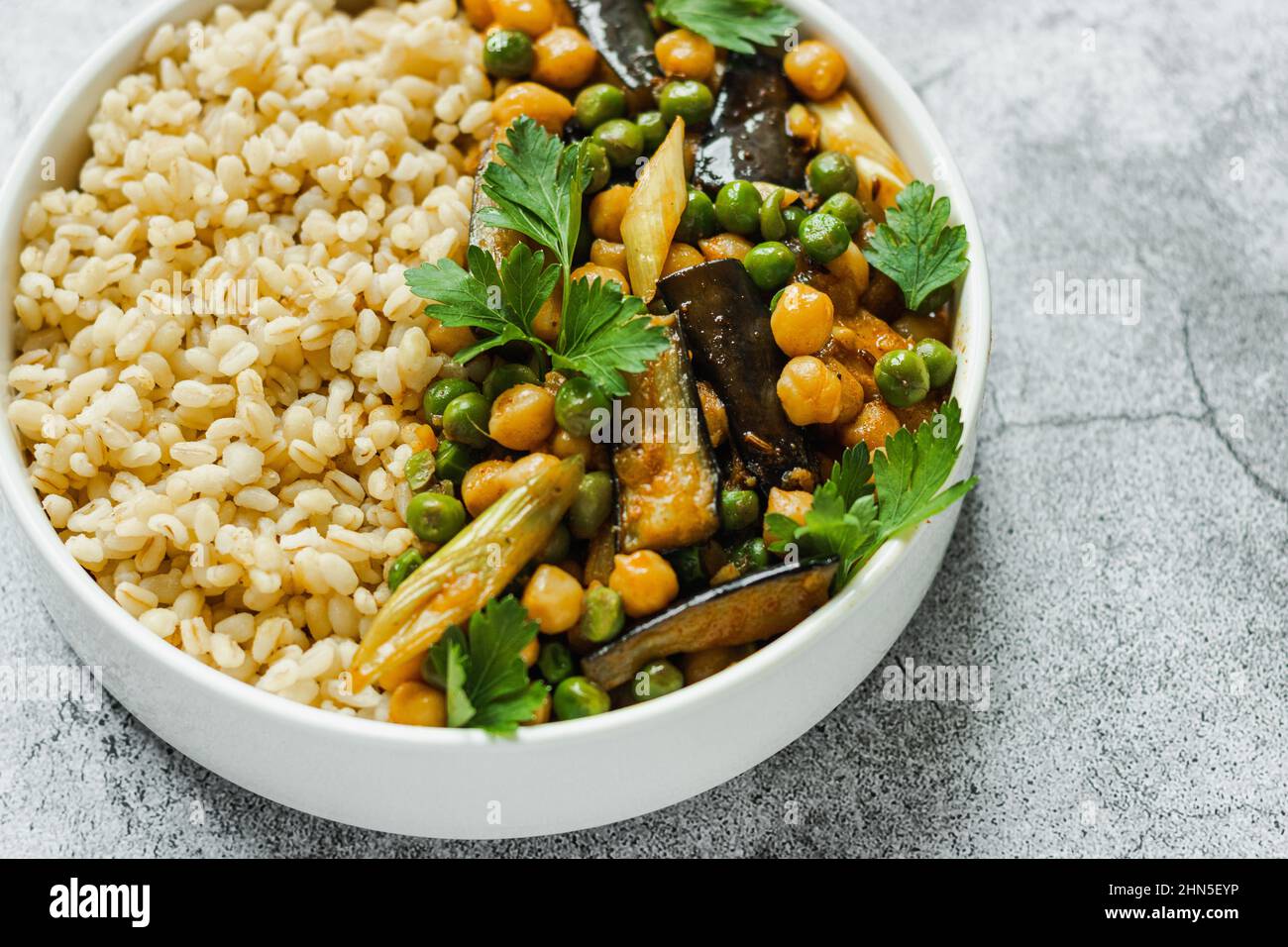 Melanzane ceci piselli vegetariano curry vegano con bulgur in una padella su sfondo grigio, vista dall'alto. Cucina indiana, cibo sano, vegano, base vegetale. Foto Stock
