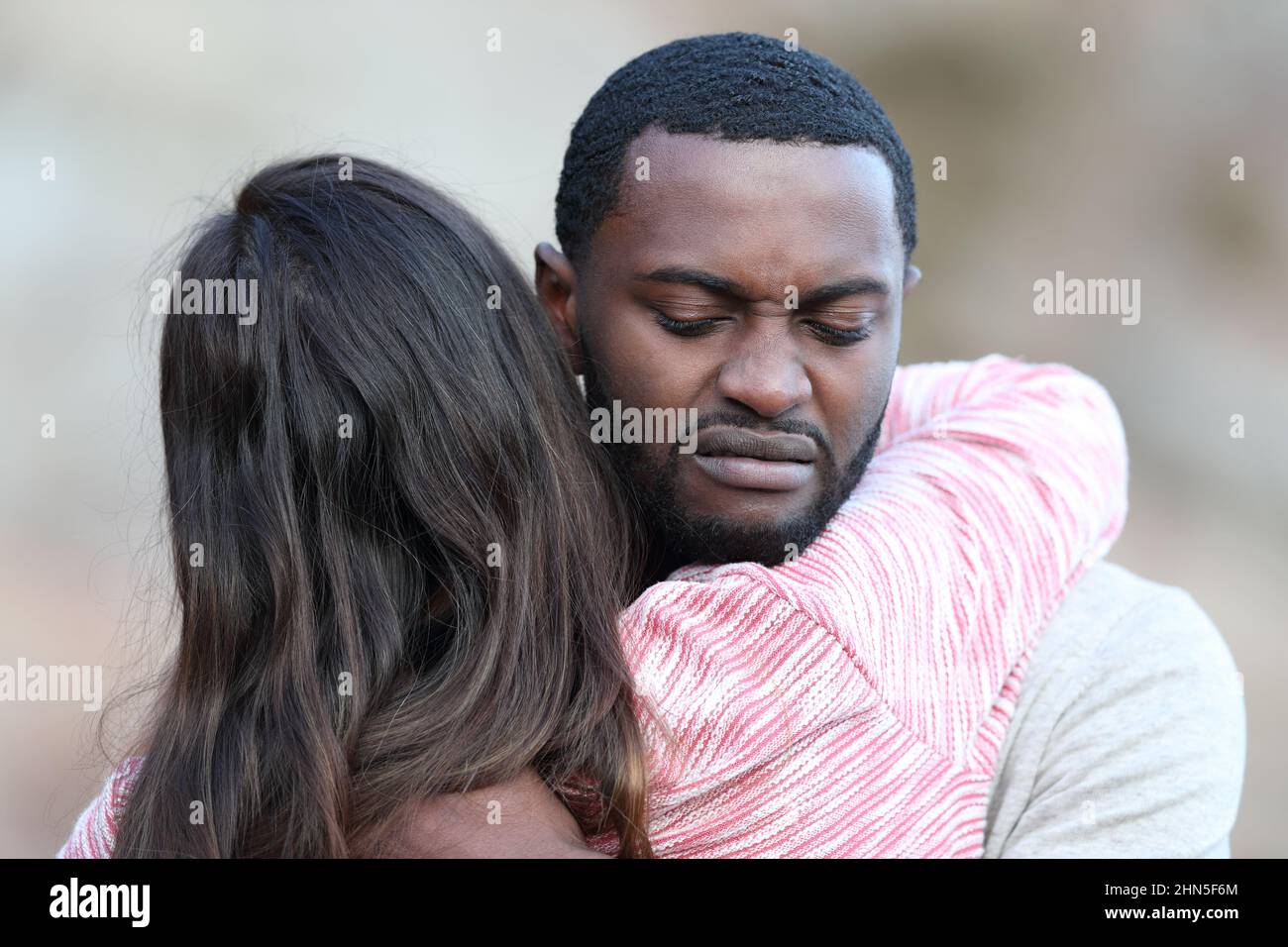 Uomo disgustato con pelle nera che abbraccia e rifiuta una donna caucasica all'aperto Foto Stock