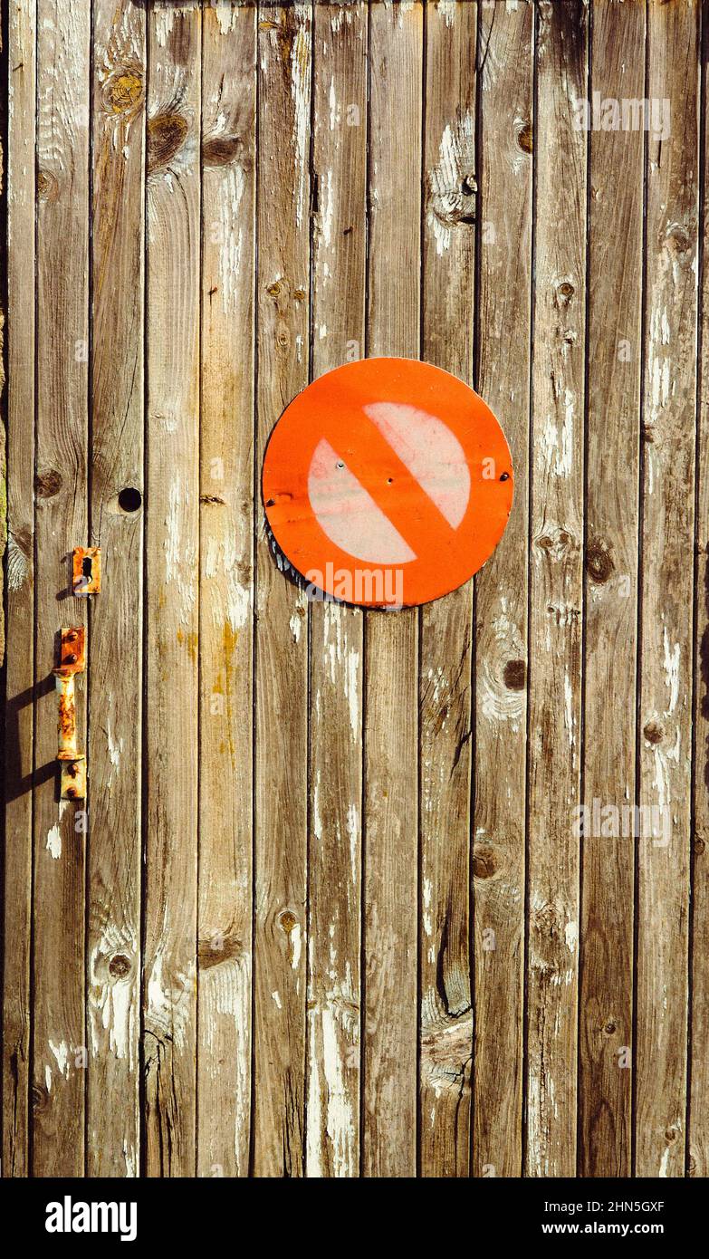 Una porta di legno intemprata con un'evidente insegna di divieto d'ingresso circondata da vernice sbucciata e serratura arrugginita, catturata durante il giorno in un ambiente urbano Foto Stock