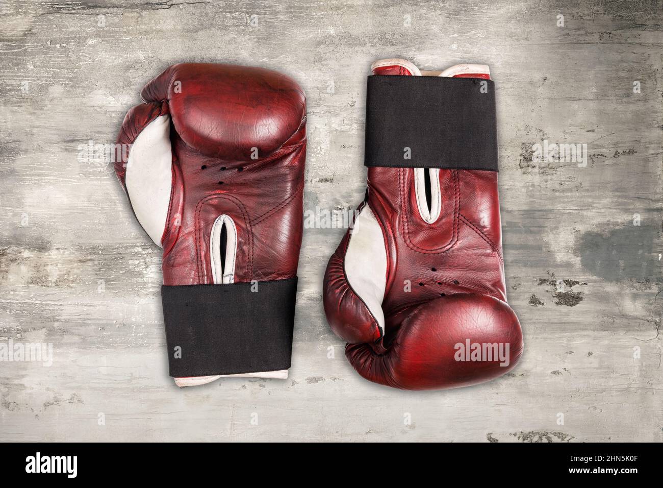 Vista dall'alto dei guanti da boxe in pelle rossa vintage posizionati sulla superficie in legno grigio resistente agli agenti atmosferici Foto Stock