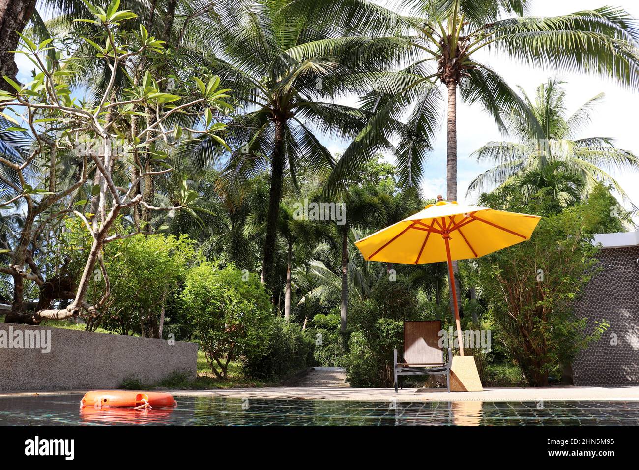 Vacanza tropicale, piscina con ombrellone e lettino circondata da palme da cocco. Vacanze in paradiso giardino, spiaggia resort Foto Stock