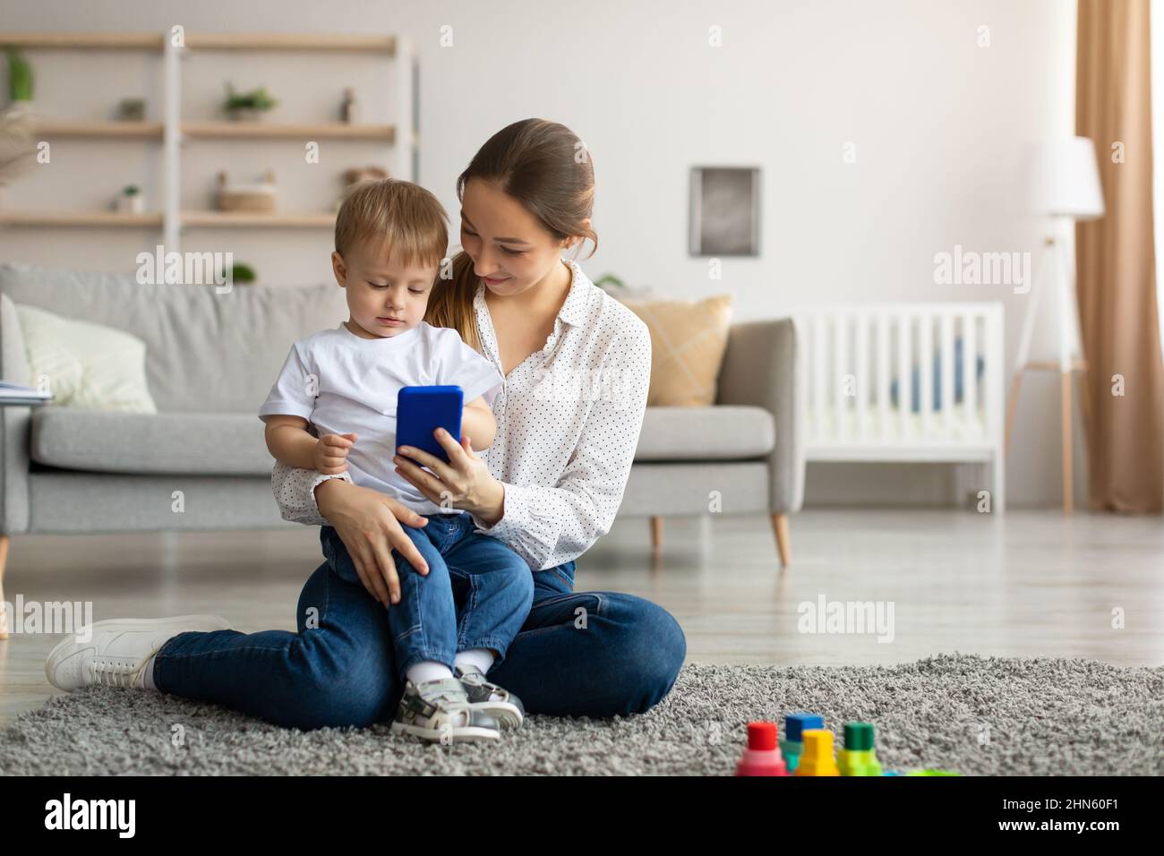 Shopping online. La mamma e il figlio del bambino usano lo smartphone a casa, acquistando insieme in internet Foto Stock