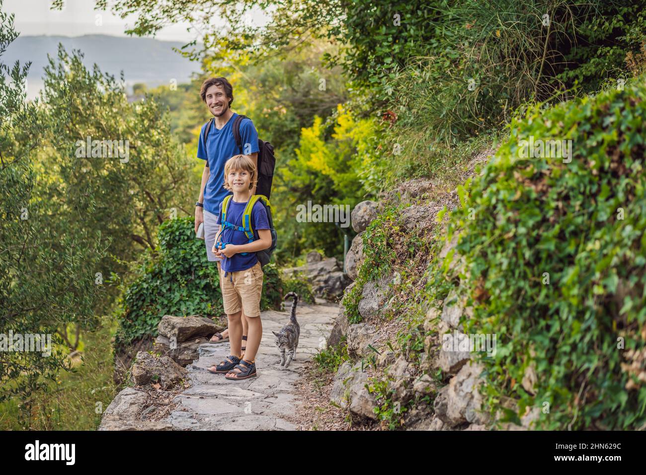 padre e suo figlio che camminano con un gatto in un parco nazionale Foto Stock