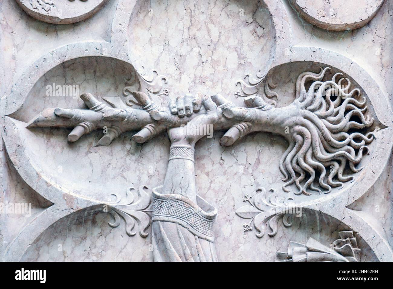 Un modello scolpito in pietra sul muro, la mano sta tenendo la radice dell'albero. In pietra. Arte in europa Foto Stock