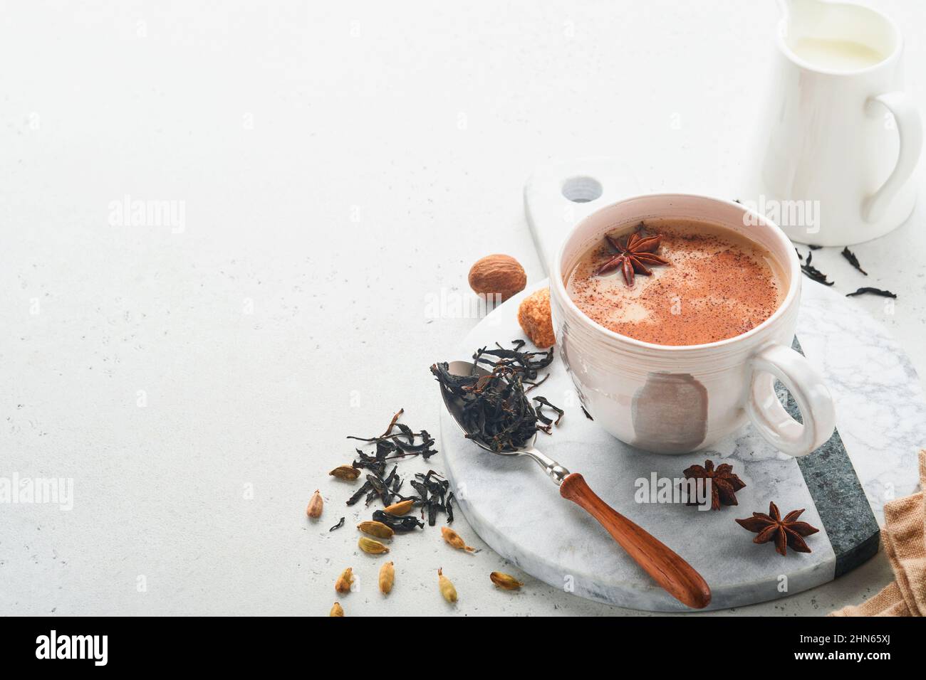 Tè Masala. Masala chai speziato tè con latte e spezie su sfondo grigio chiaro. Tradizionale bevanda indiana. Bevanda speziata. Spazio di copia. Messa a fuoco selettiva. Foto Stock