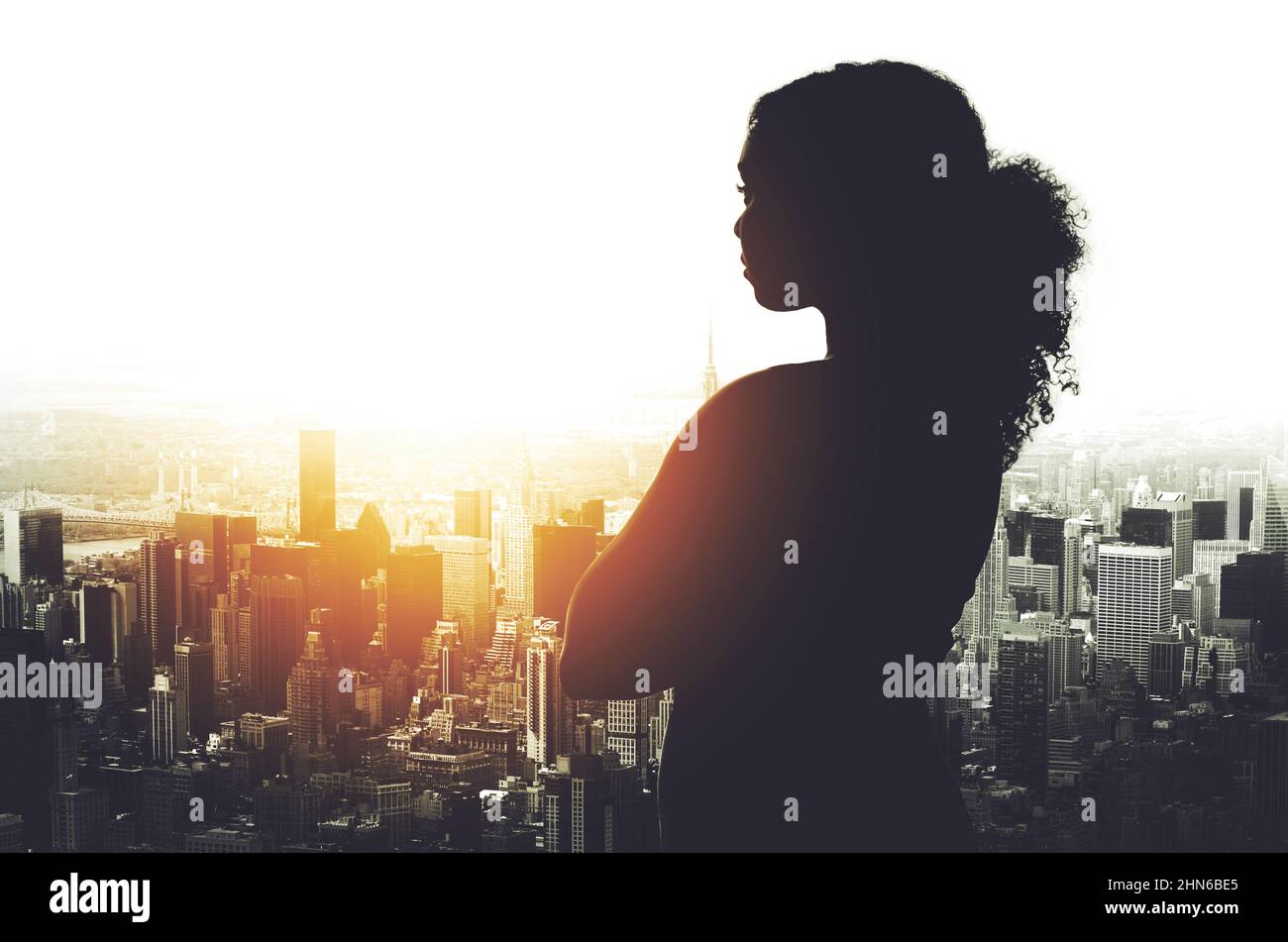 Il suo successo è stato plasmato in questa città. Un'immagine silhouetted di una giovane donna d'affari che guarda un paesaggio urbano da una finestra d'ufficio. Foto Stock