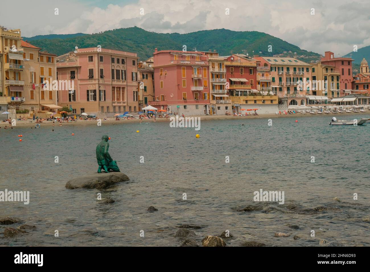 Monumento il Pescatore del Leonardo Lustig nella baia del silenzio a Sestri Levante, Liguria, Italia attraverso le case colorate, montagne e coa Foto Stock