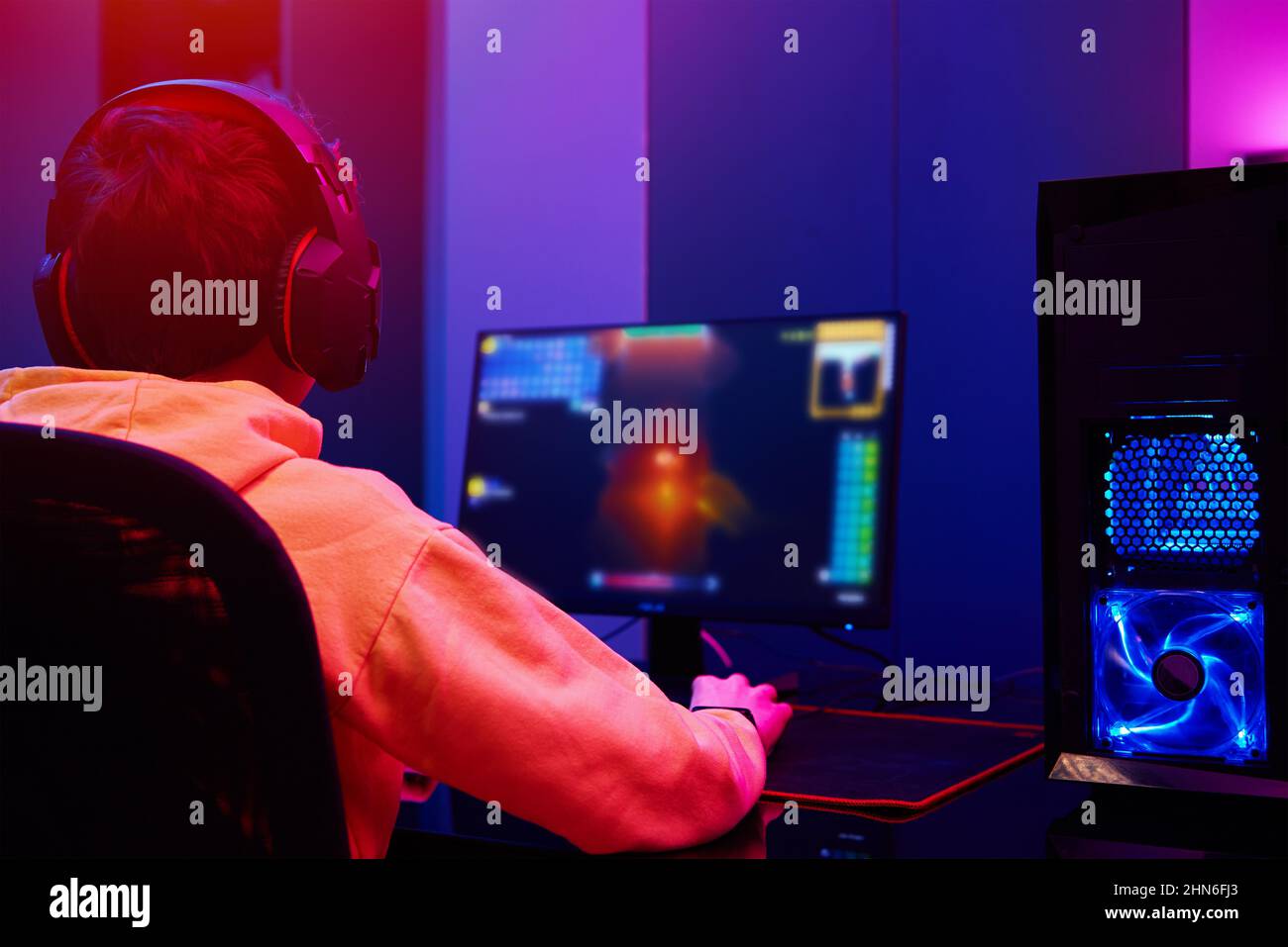 Vista posteriore di ragazzo adolescente giocare video gioco computer in camera oscura, utilizzare neon colorato tastiera meccanica rgb, luogo per il gioco di cybersport Foto Stock