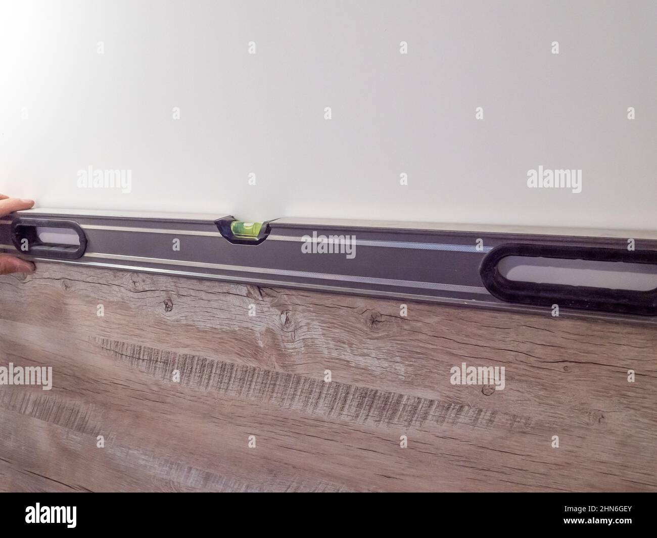 Il falegname controlla il livello con una livella a bolla d'aria nel banco della cucina. Assemblaggio di mobili professionali in cucina Foto Stock