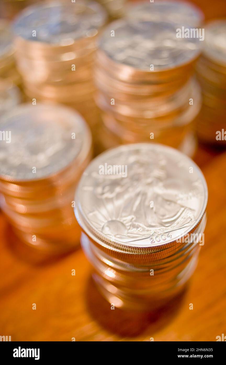 Pile di brillanti dollari della libertà d'argento si siedono su un caldo tavolo in legno Foto Stock