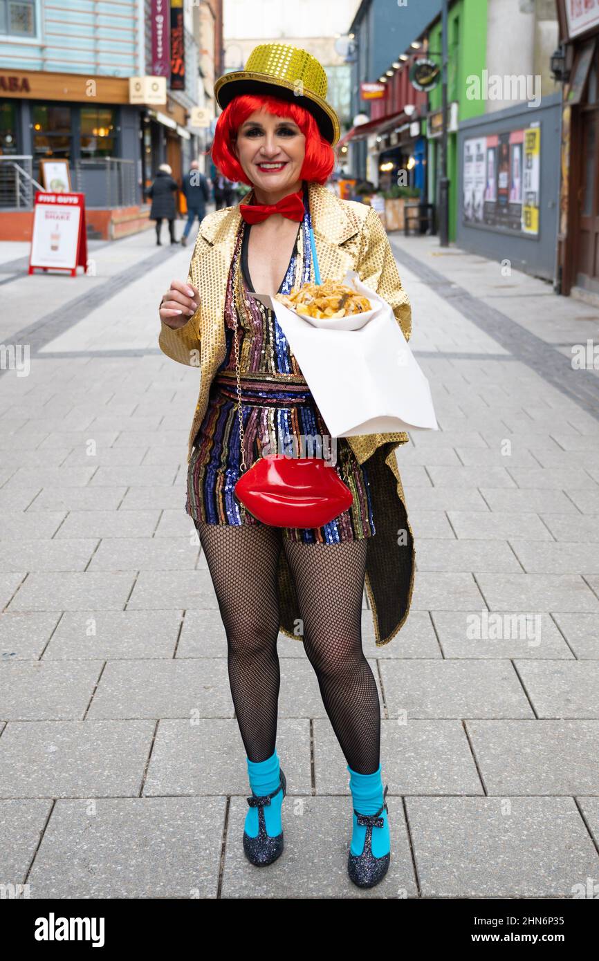 Una donna vestita come personaggio del Rocky Horror Show pone per una fotografia che tiene cibo da asporto su Caroline Street a Cardiff, Galles, Regno Unito. Foto Stock