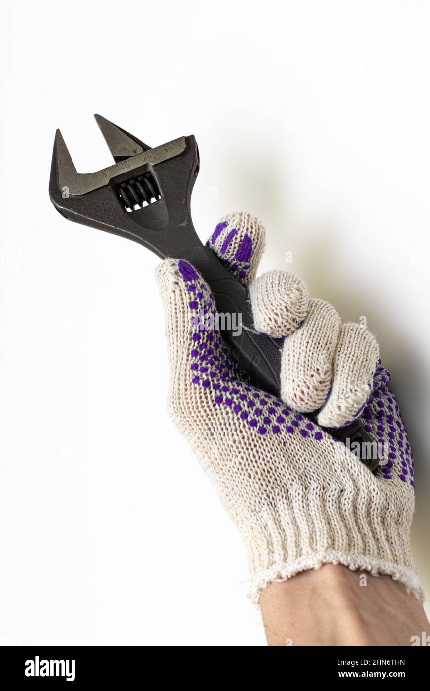 una mano con guanti tiene una chiave regolabile con scala e divisioni. Foto di alta qualità Foto Stock