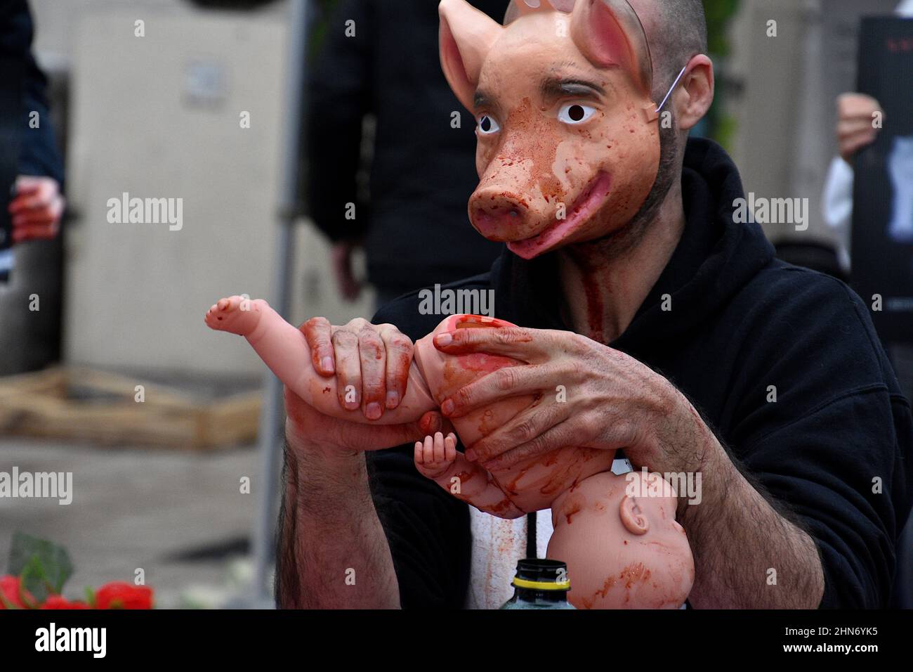 Marsiglia, Francia. 13th Feb 2022. Si vede un manifestante che indossa una maschera di maiale spruzzata di vernice rossa per raffigurare il sangue mentre si tiene una bambola a un gamba per raffigurare 'carne umana' durante la protesta dello speciesismo a Marsiglia.gli attivisti dell'associazione Life France 269 si sono riuniti sulla Canebière a Marsiglia per aumentare la consapevolezza per la protezione degli animali da simulare un pasto fittizio di animali che si nutrono di carne umana. Credit: SOPA Images Limited/Alamy Live News Foto Stock