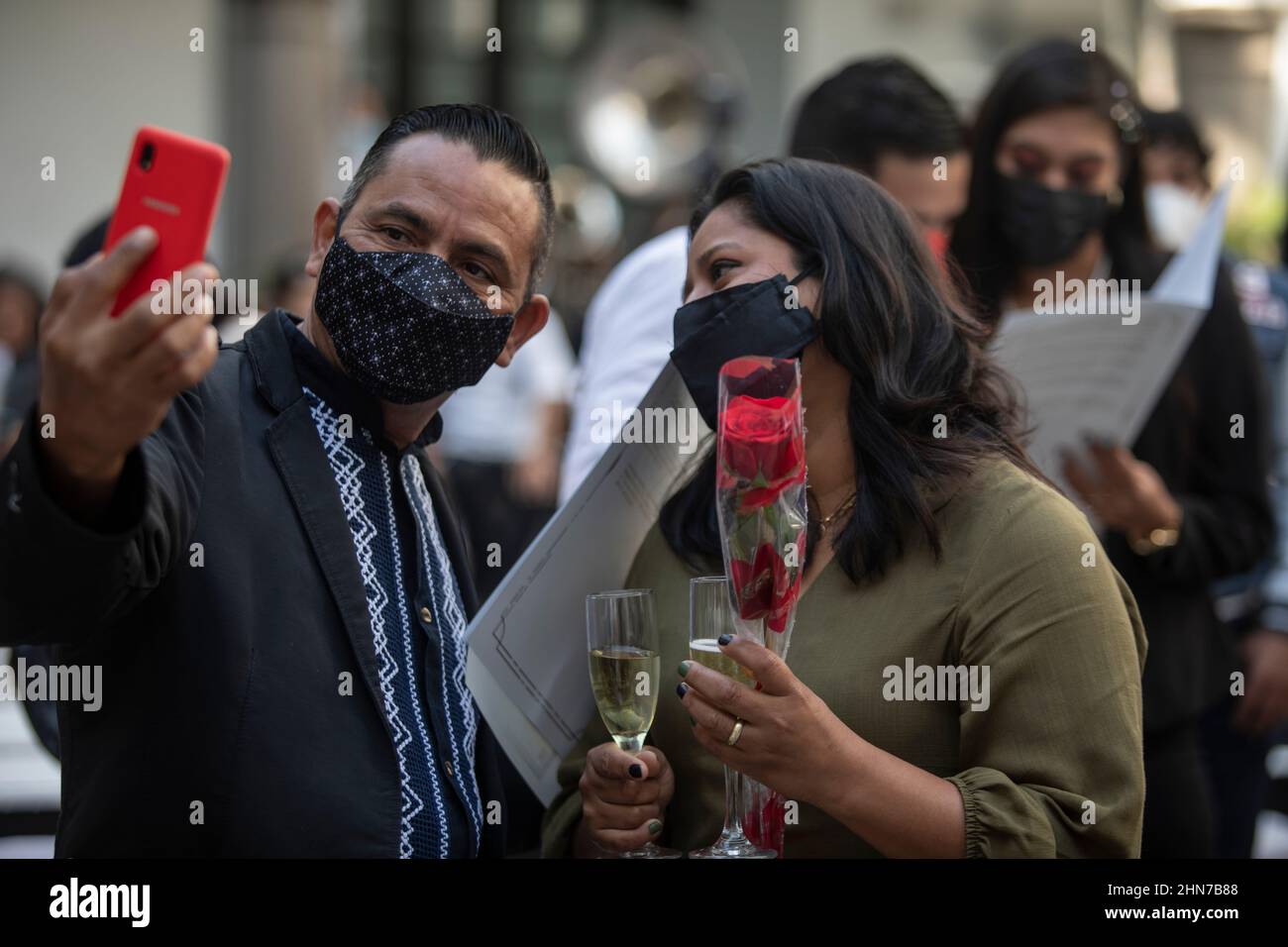 Veracruz, Messico. 14th Feb 2022. Una coppia con copertura bocca-naso prende un selfie dopo il loro matrimonio, che ha avuto luogo in una data organizzata per diverse coppie dal municipio. Più di 300 coppie si erano registrate per questa data. Tuttavia, a causa delle restrizioni imposte dalla pandemia di Corona, sono state ammesse solo 20 coppie. Credit: Felix Marquez/dpa/Alamy Live News Foto Stock