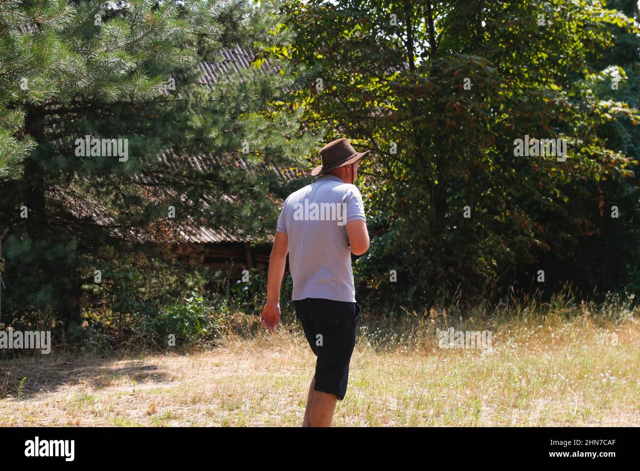 Maschio in cappello. Ritratto di contadino sorridente con erba verde e alberi natura sullo sfondo. Giovane uomo che indossa un cappello da cowboy sul campo. Primo piano. Felice persona Foto Stock