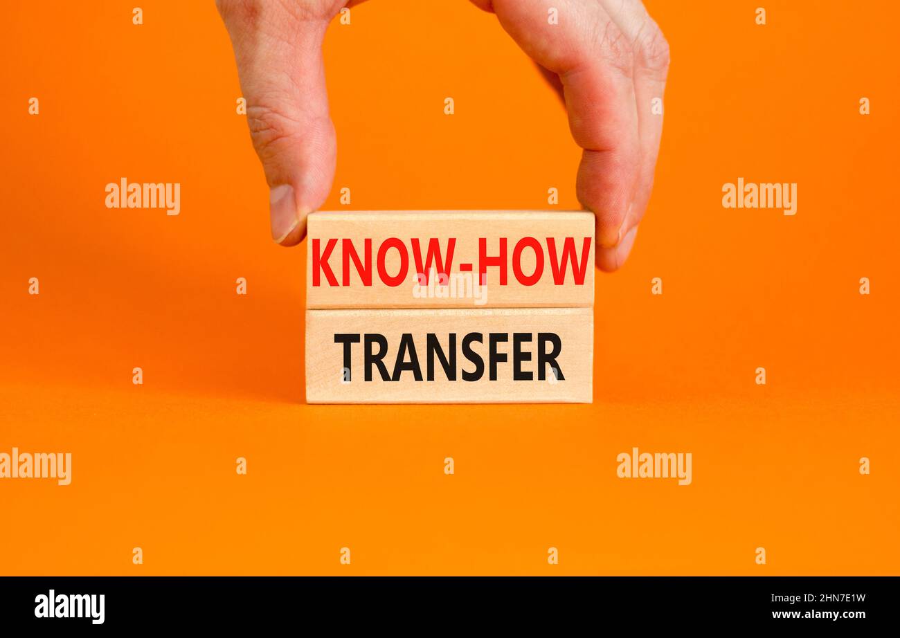 Simbolo di trasferimento del know-how. Concetto parole know-how trasferimento su blocchi di legno su bello arancione tavolo sfondo arancione. Mano dell'uomo d'affari. Spazio di copia. Foto Stock