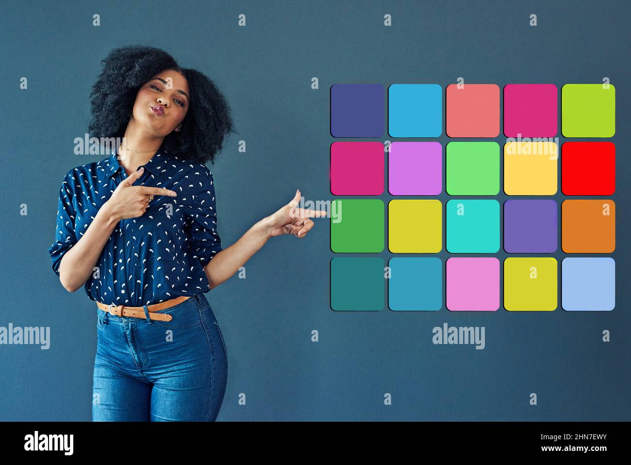 Segni dei tempi digitali. Studio girato di una giovane donna che punta verso varie icone di notifica su uno sfondo grigio. Foto Stock