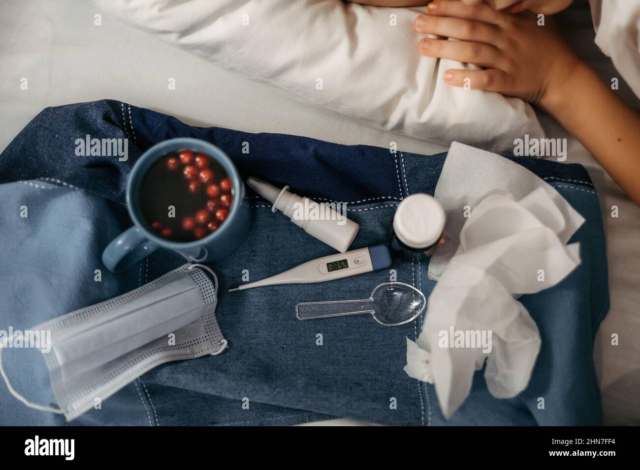 Bambino malato sdraiato a letto. Alcuni farmaci e termometro si trovano nelle vicinanze. Primo piano Foto Stock