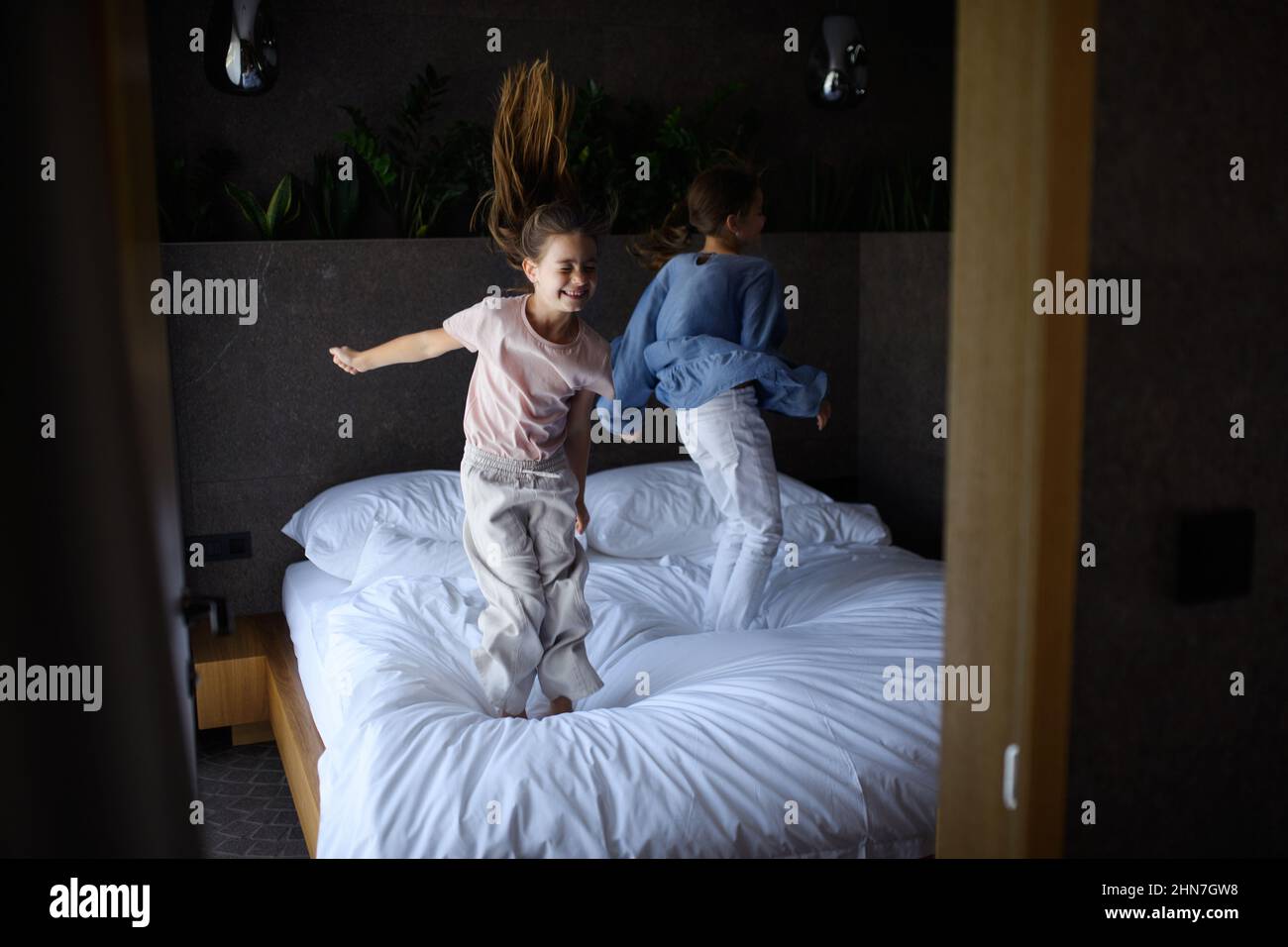 Due sorelline che saltano sul letto all'interno dell'hotel. Foto Stock