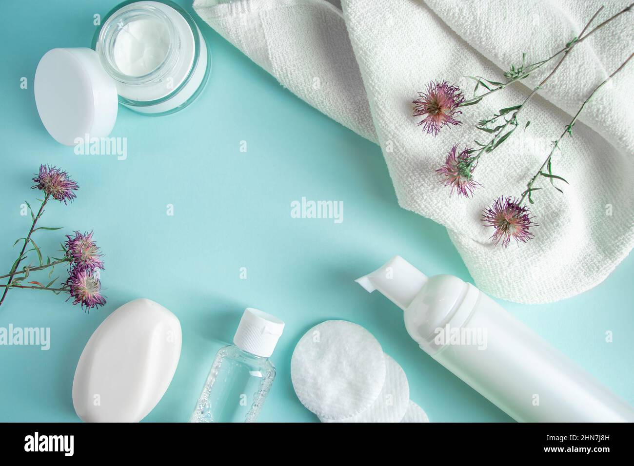 Prodotti cosmetici e fiori secchi su sfondo blu. Panna, lozione, sapone e tamponi di cotone. Cosmetici naturali a base di erbe. Cura della pelle, concetto di benessere. COP Foto Stock
