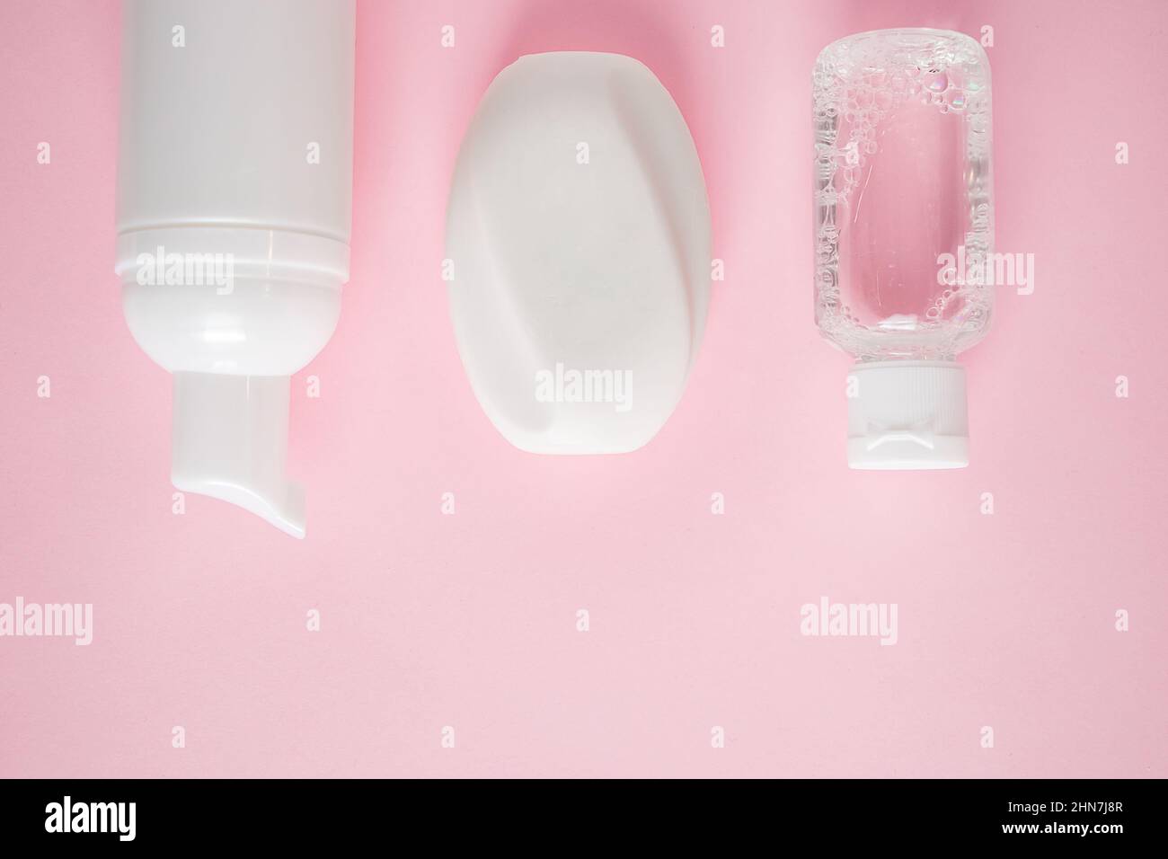 Prodotti cosmetici su sfondo rosa. Sapone, lozione e tamponi di cotone. Accessori per il centro benessere. Concetto di benessere. Foto Stock