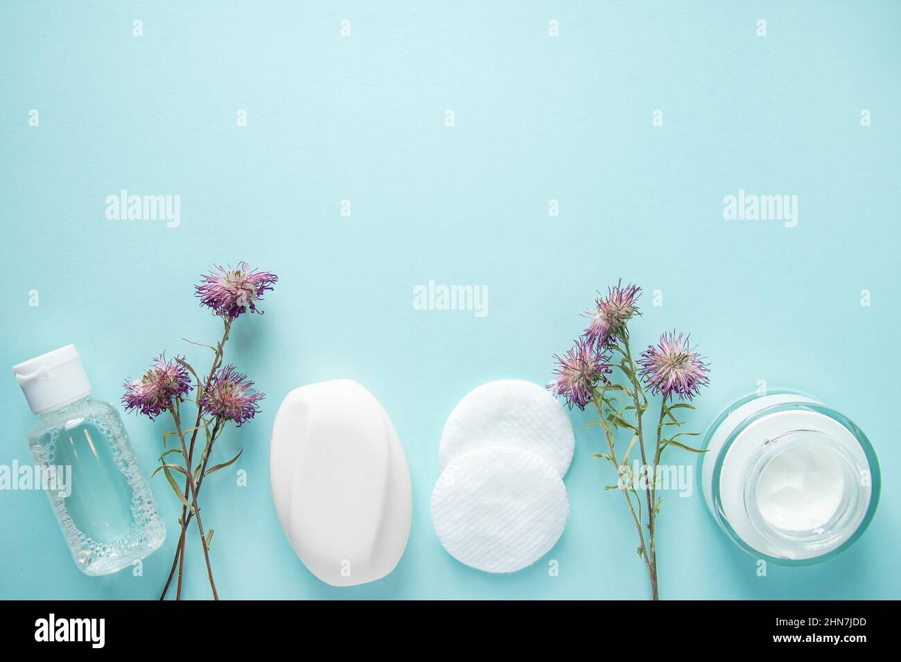 Prodotti cosmetici e fiori secchi su sfondo blu. Panna, lozione, sapone e tamponi di cotone. Cosmetici naturali a base di erbe. Cura della pelle, concetto di benessere. COP Foto Stock