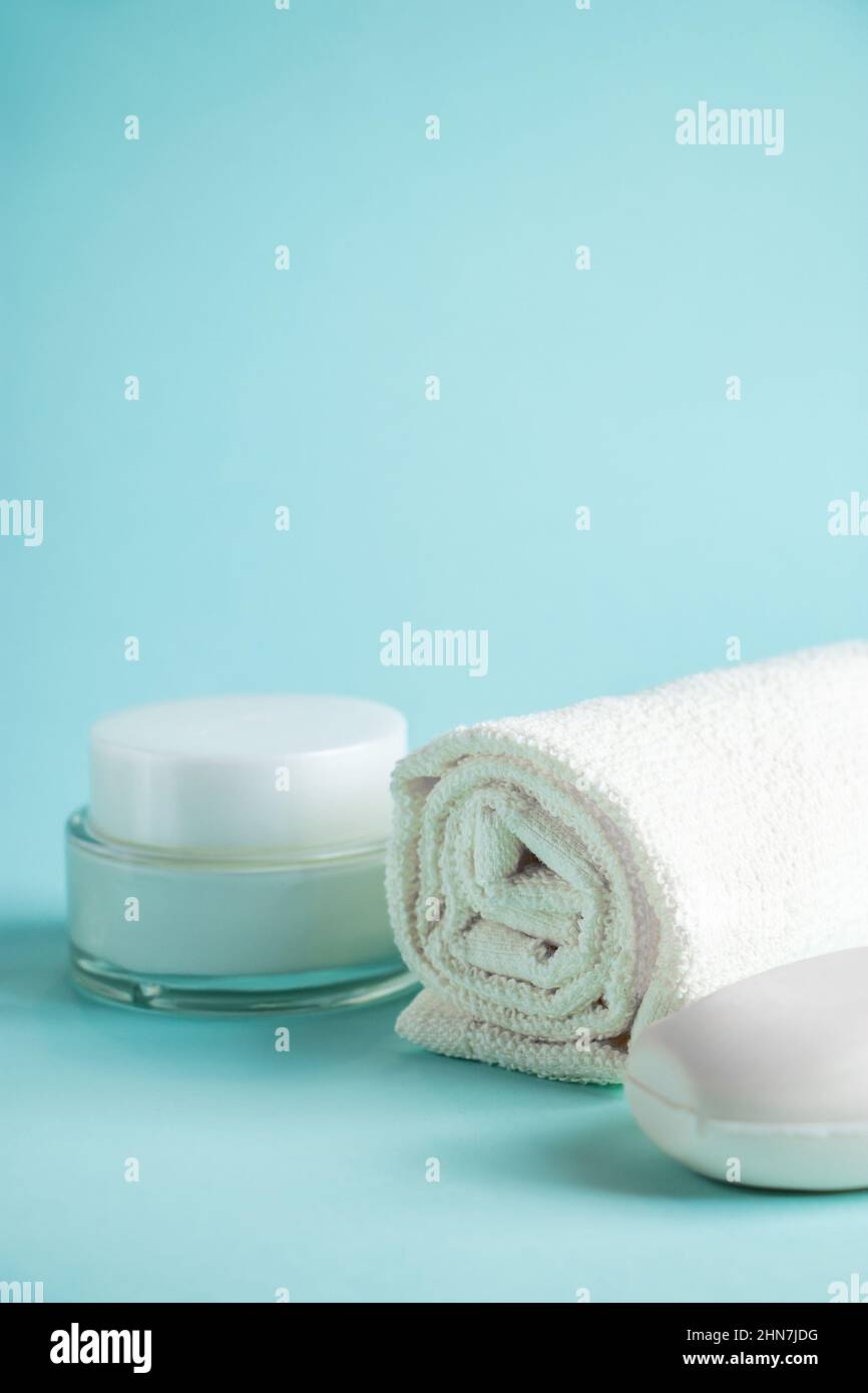 Prodotti cosmetici e accessori spa su sfondo blu. Crema, sapone e asciugamano. Cura della pelle, concetto di benessere. Spazio di copia. Foto Stock