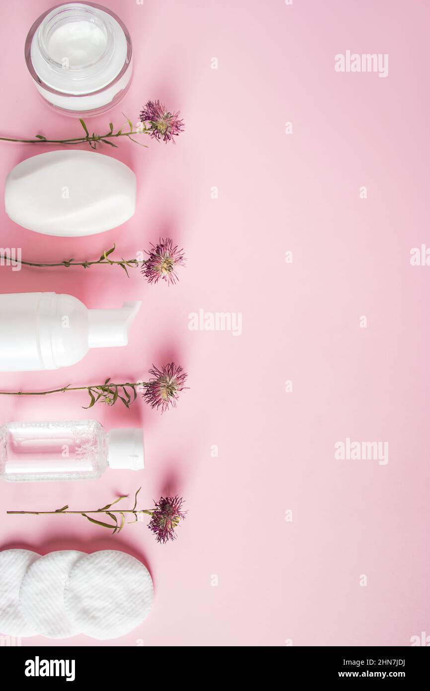 Prodotti cosmetici su sfondo rosa. Bottiglie bianche di crema e lozione. Accessori spa, cura del corpo. Concetto di benessere. Foto Stock