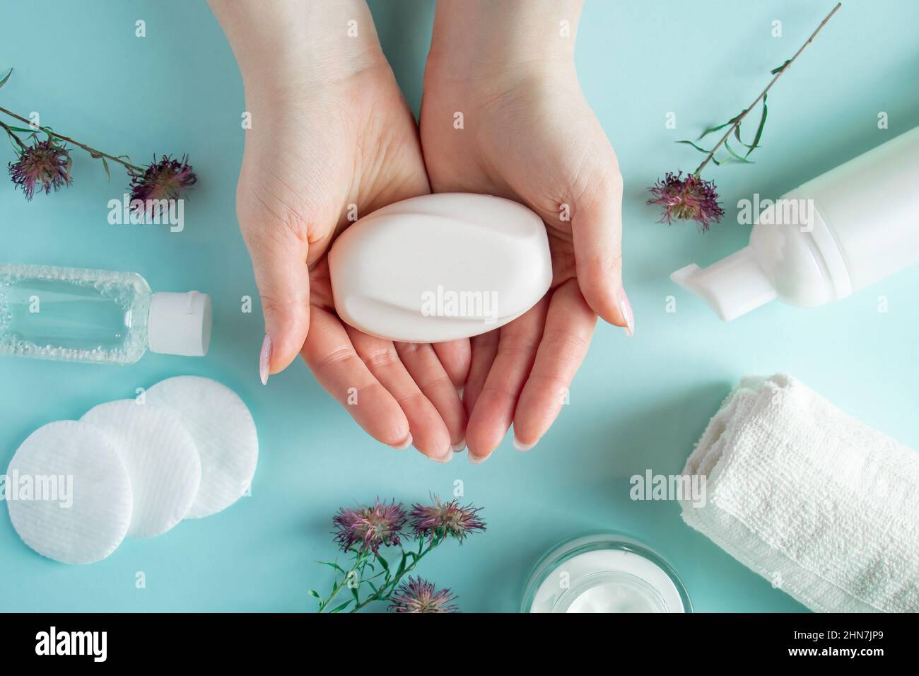 Sapone per mani femminili. Prodotti cosmetici su sfondo blu. Accessori spa, cura del corpo. Concetto di benessere. Foto Stock