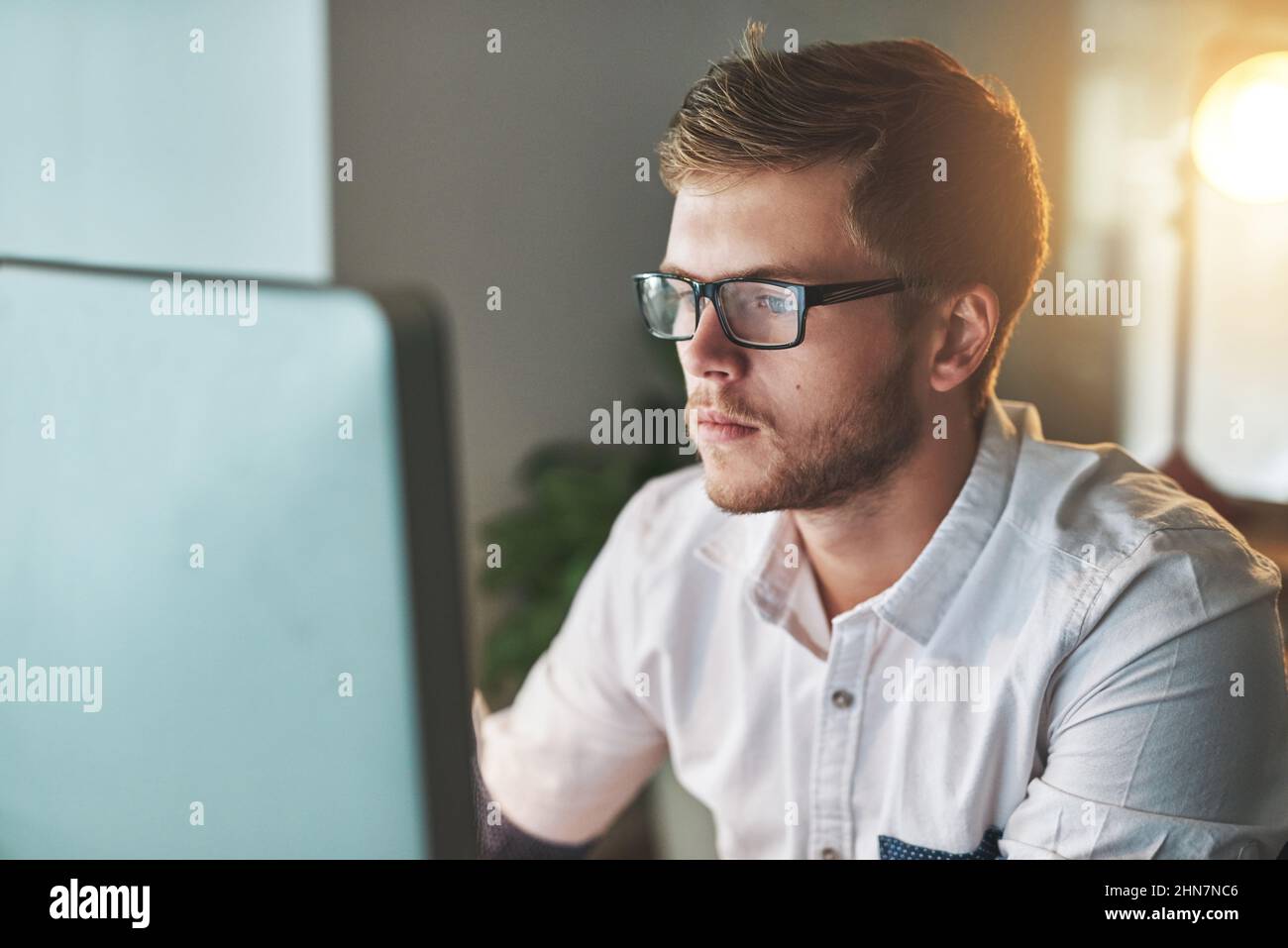 Lavorare di notte è un buon modo per evitare distrazioni. Scatto ritagliato di un giovane designer che lavora tardi in ufficio. Foto Stock