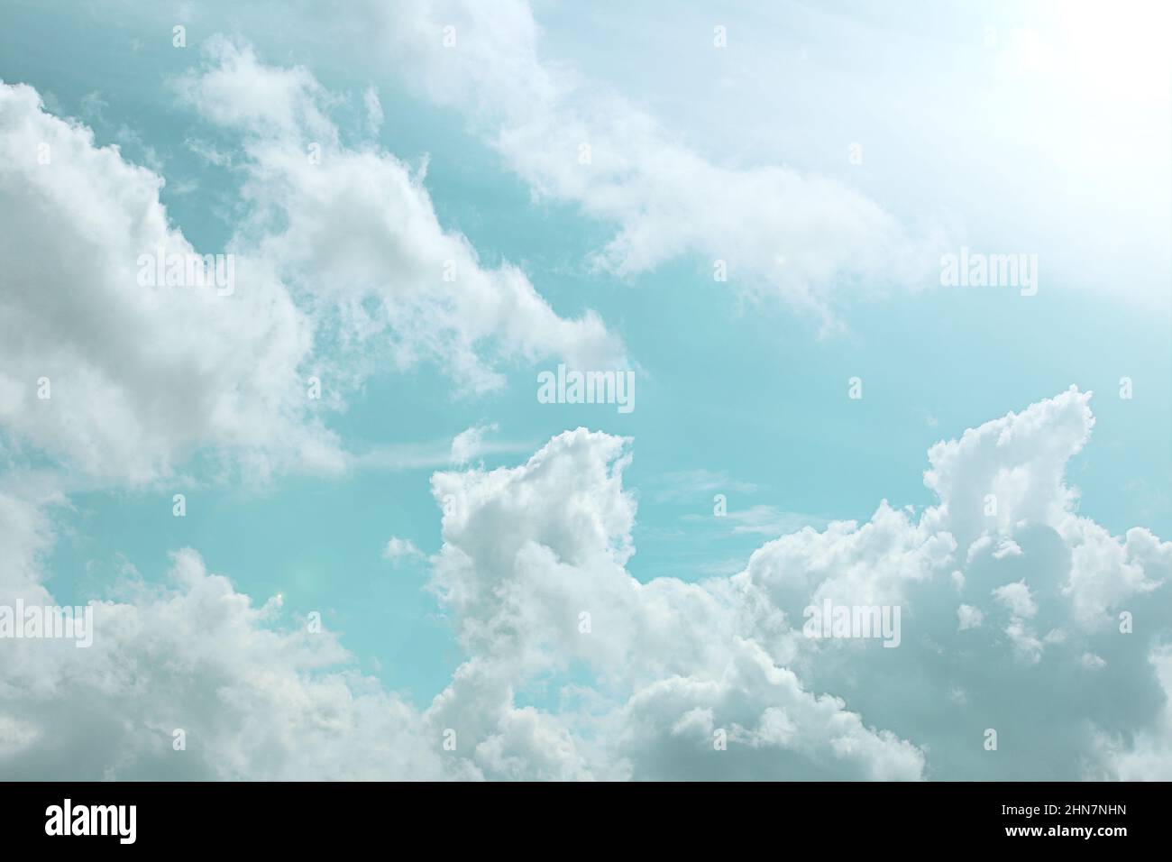 Cielo sfondo. Nuvole bianche e raggi di sole in un cielo azzurro. Il cielo è di colori pastello. Foto Stock