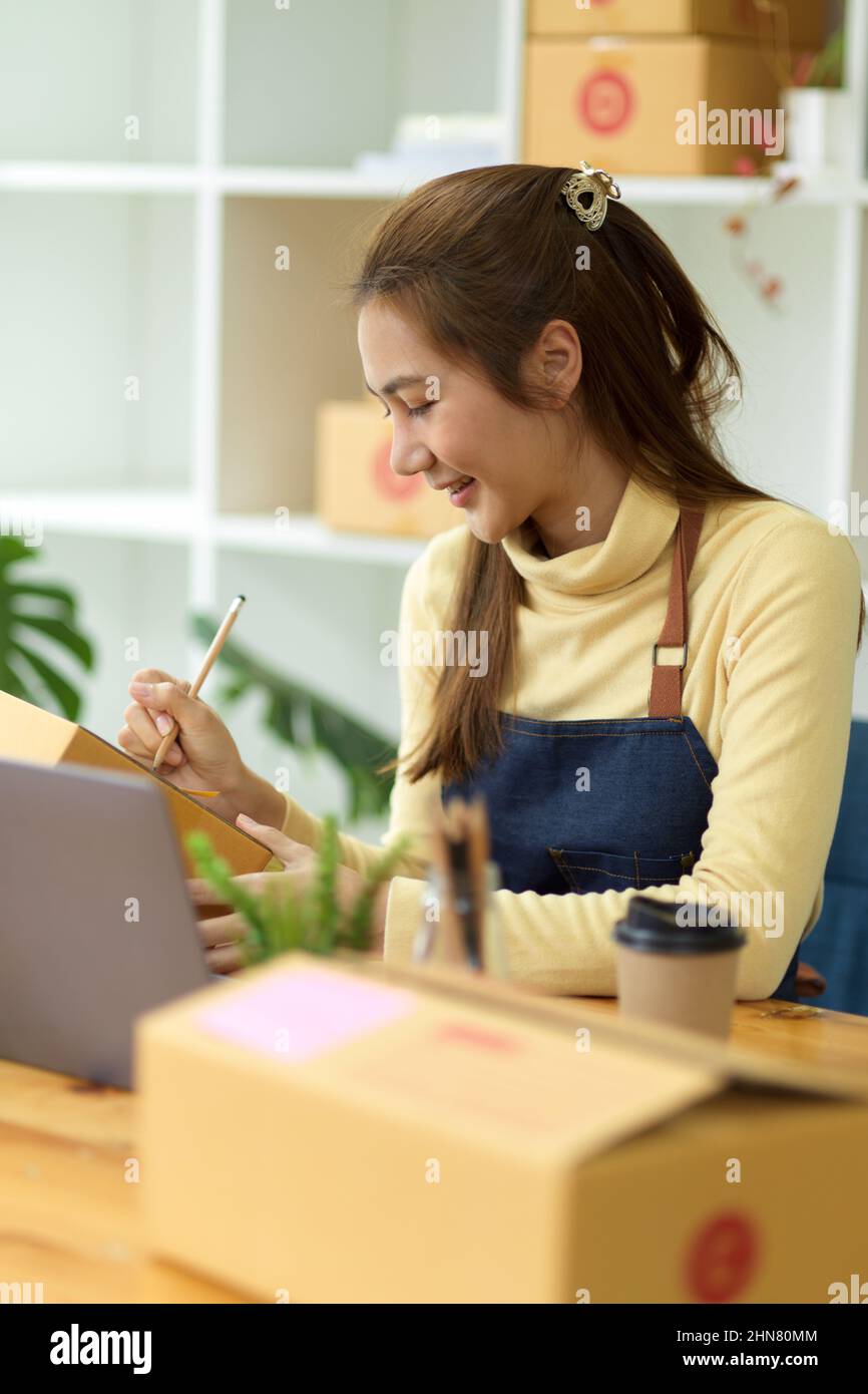 Ritratto, Un imprenditore femminile di piccole imprese ha preparato il pacchetto di un cliente, controllando il numero di tracking consegna sul computer portatile. E-commerce bus Foto Stock