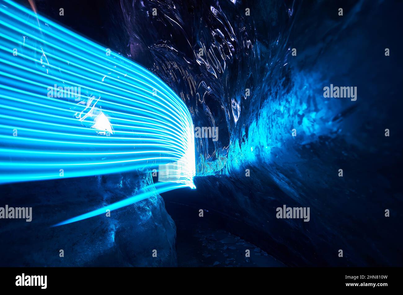 Paesaggio di incredibile grotta di ghiaccio glaciale con luci blu a LED fascio all'interno di una parete di ghiaccio profondo nel ghiacciaio invernale di montagna in Kazakistan Foto Stock