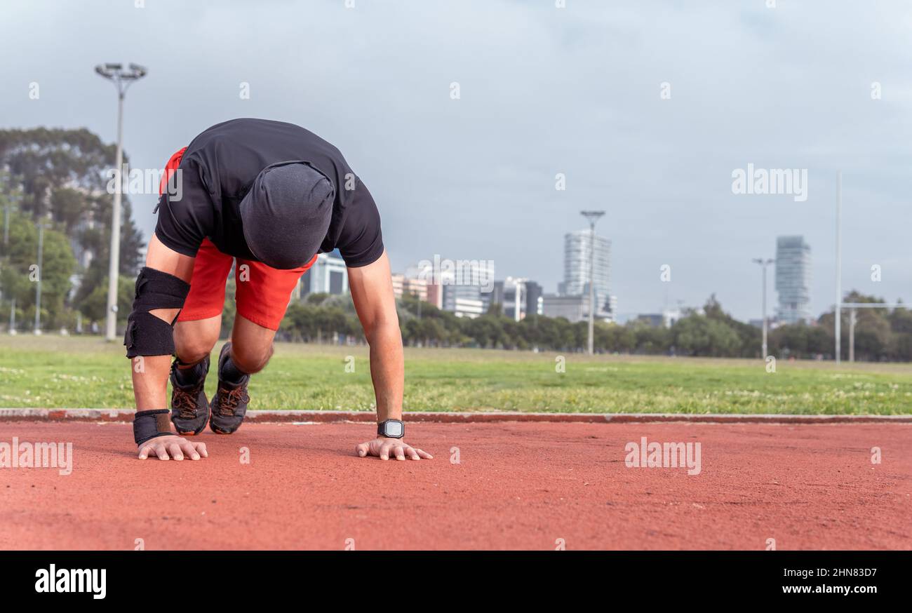 L'uomo che fa arrampicatore di montagna esercizio in abbigliamento sportivo in un parco in una mattinata di sole Foto Stock