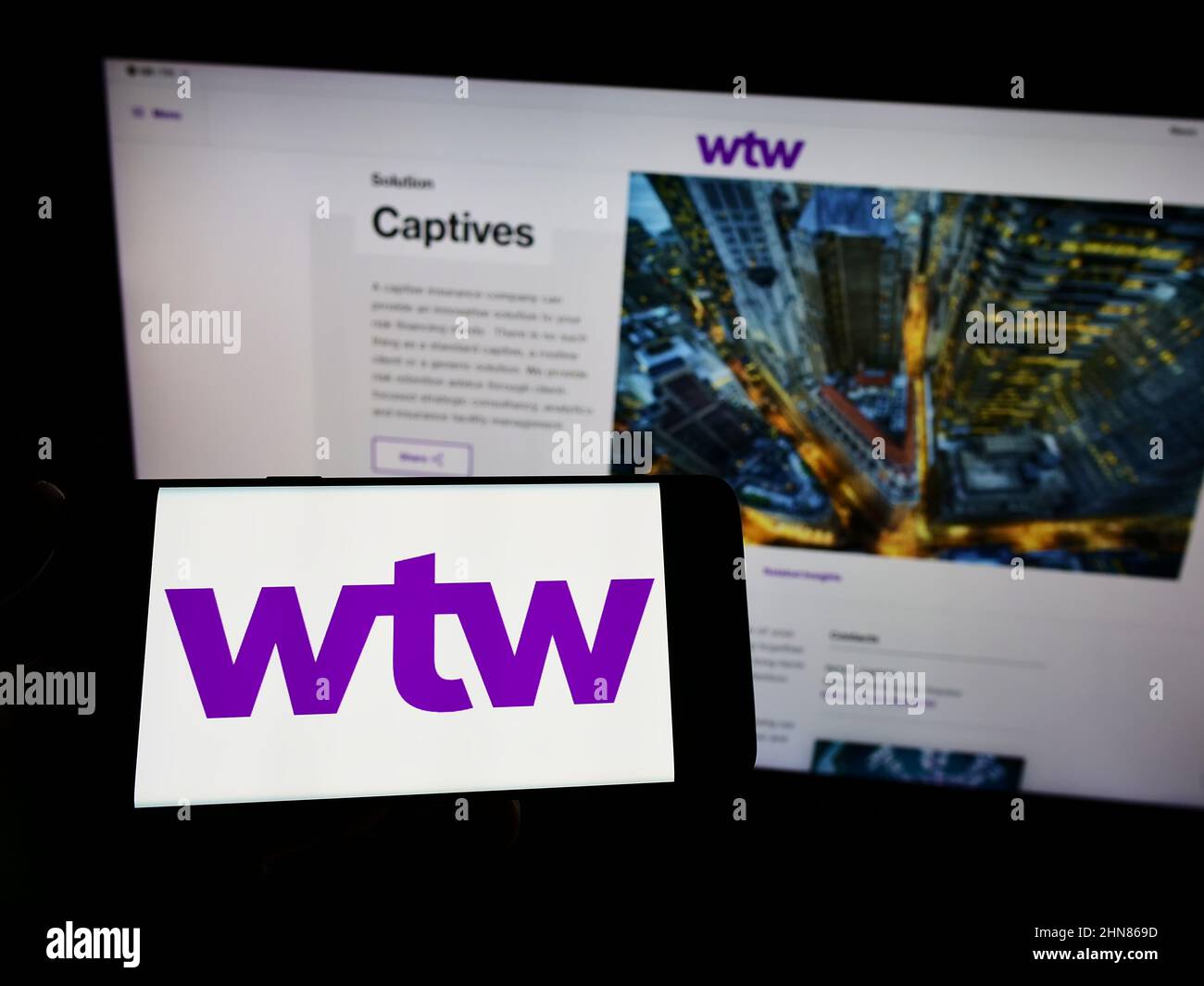 Persona che tiene smartphone con il logo della società finanziaria Willis Towers Watson plc (WTW) sullo schermo di fronte al sito web. Mettere a fuoco sul display del telefono. Foto Stock