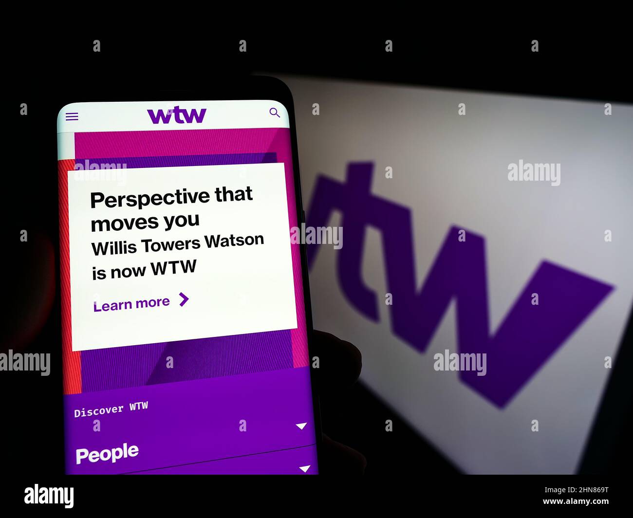 Persona che detiene smartphone con sito web della società finanziaria Willis Towers Watson plc (WTW) sullo schermo con logo. Concentrarsi sul centro del display del telefono. Foto Stock
