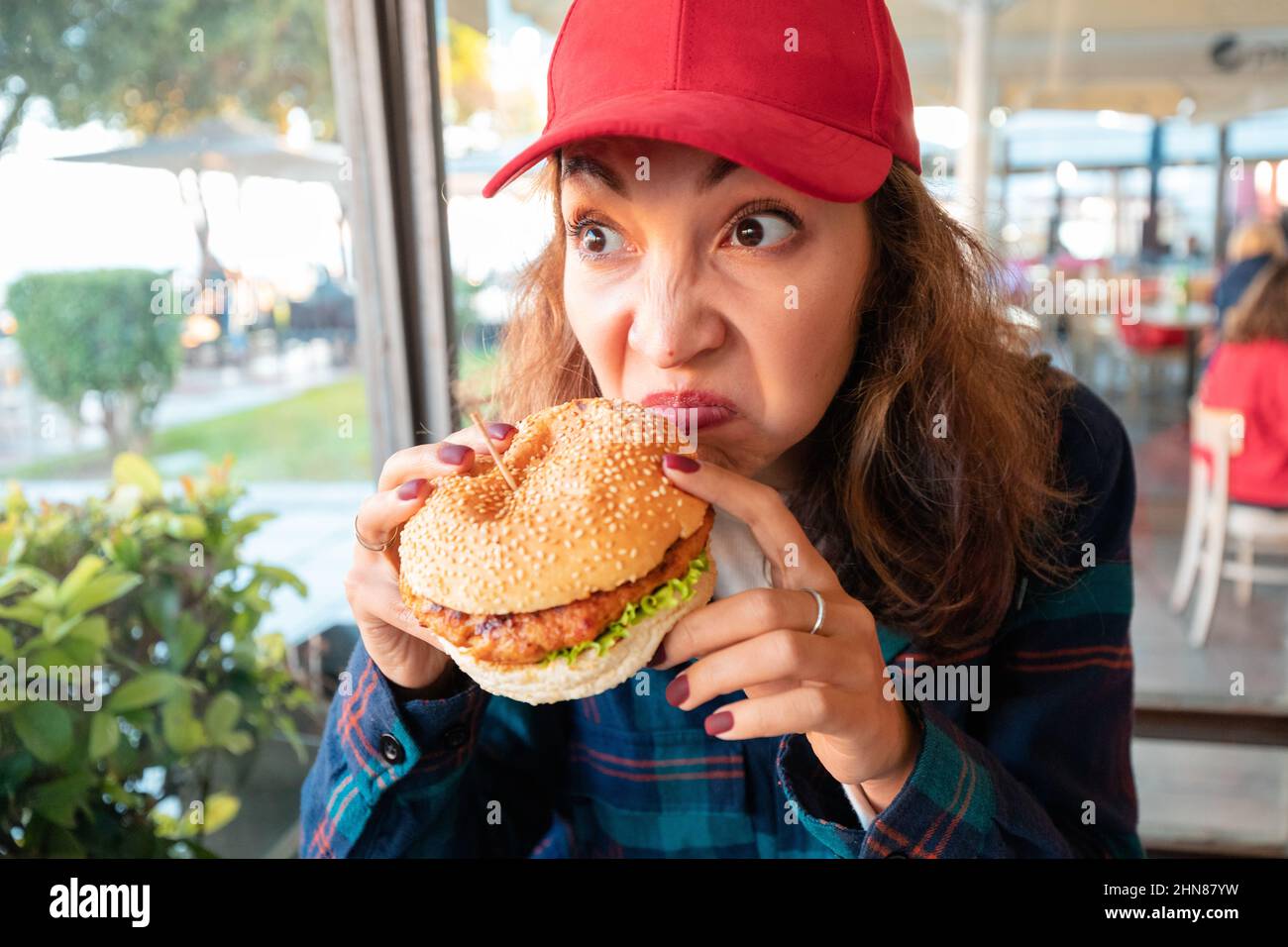 Una donna sniffa hamburger in un bar con disgusto sul suo volto. Il concetto di cibo viziato e avvelenamento nel ristorante catering Foto Stock