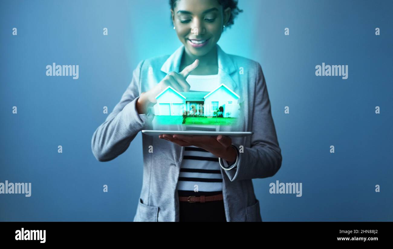 La tua casa perfetta è a portata di app. Studio girato di una giovane donna d'affari utilizzando un tablet digitale con grafica di proprietà su sfondo blu. Foto Stock