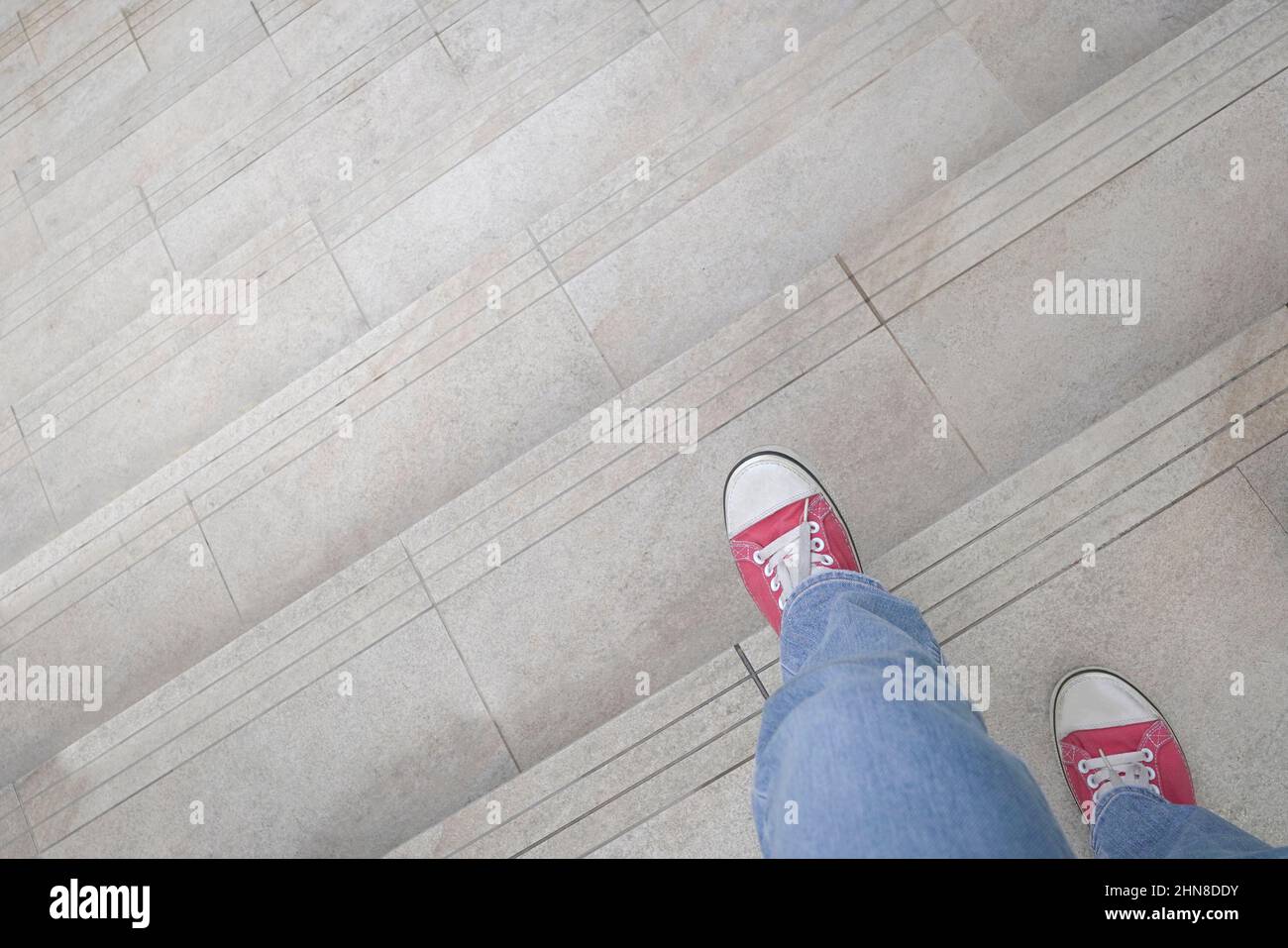 Vista ravvicinata della donna con scarpe rosse che scendono le scale. Concetto di discesa o di uscita. Foto Stock